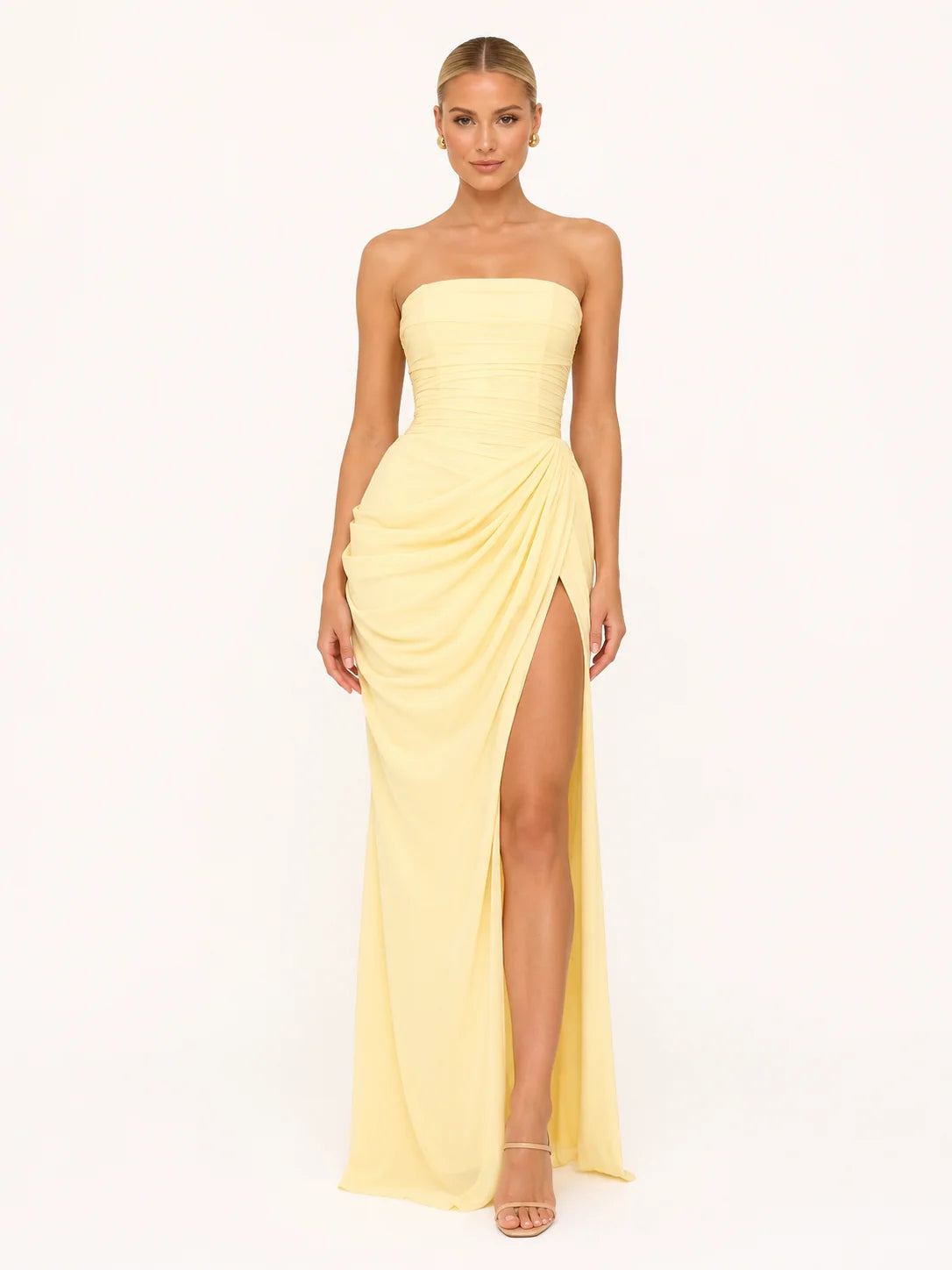 Robe corset longue jaune pastel portée par une femme blonde coiffée d'un chignon. Le bustier met en valeur ses épaules avec élégance et la fente profonde dévoile subtilement sa jambe. Image
