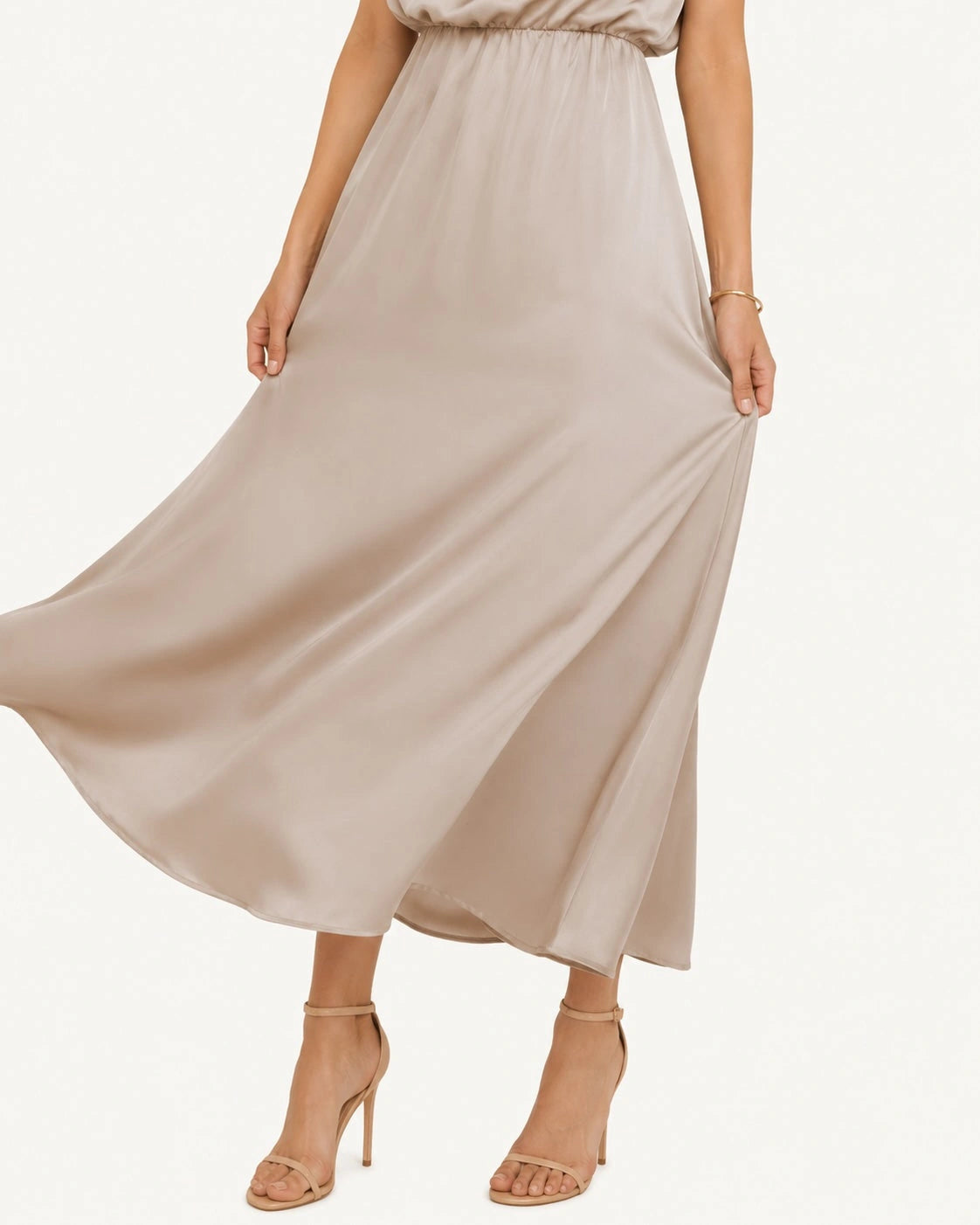 Jupe fluide d'une robe longue satinée champagne, tissu soyeux et mouvement aérien apportant légèreté et élégance à une tenue de cérémonie raffinée. Détail de la jupe fluide.