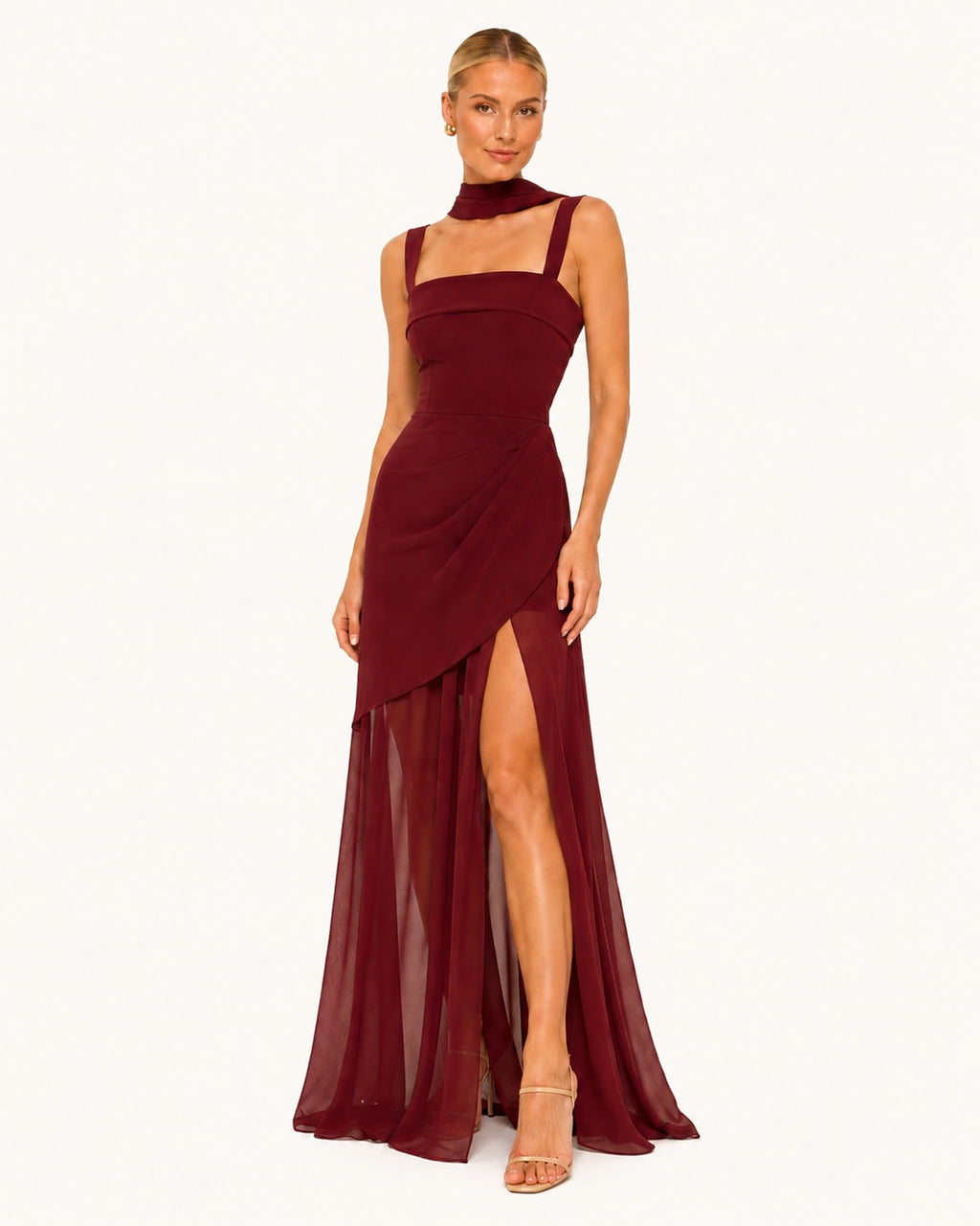 Robe bordeaux longue fendue avec superposition asymétrique et voile transparent, offrant une silhouette élancée et féminine pour les grandes occasions.
