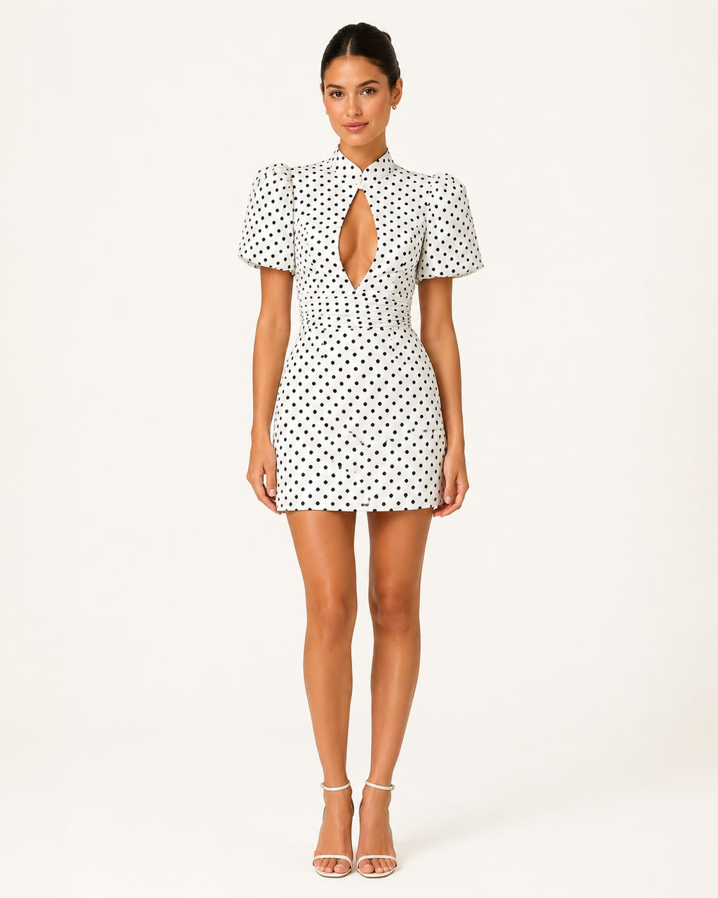 Vue de face de la robe courte Stella blanche à pois noirs, col montant, manches ballon, taille ajustée et décolleté goutte, idéale pour une tenue chic de soirée ou de cocktail.