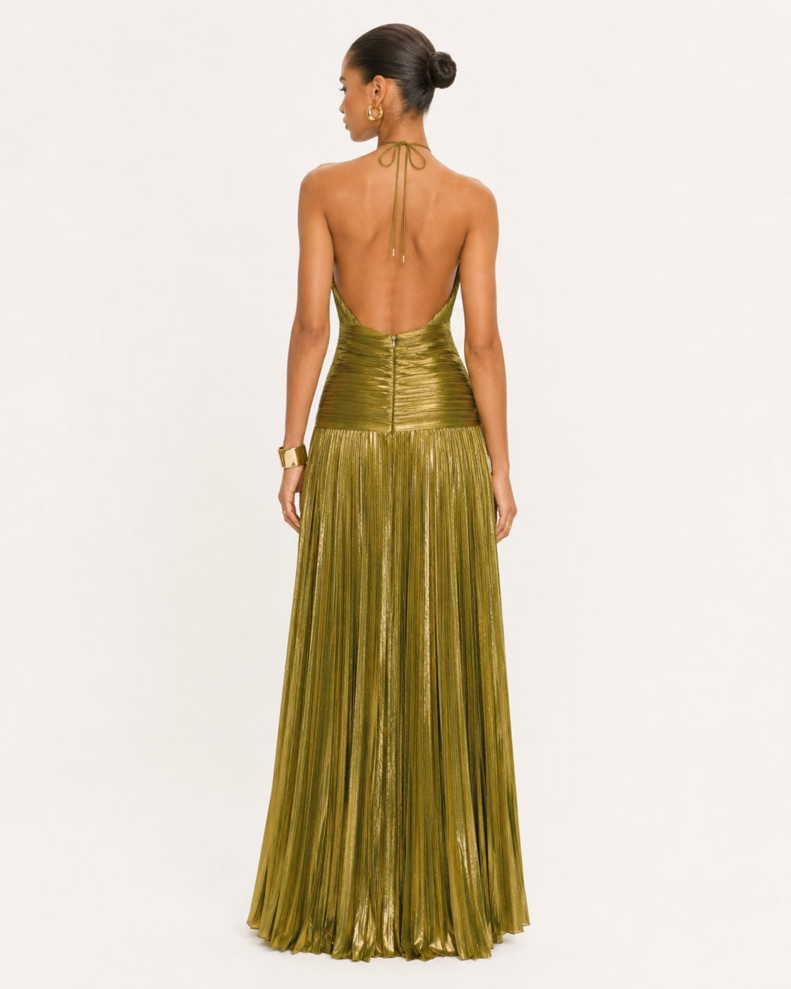 Dos nu spectaculaire d’une robe de soirée dorée à col halter, avec jupe longue plissée et coupe sophistiquée idéale pour mariage, gala ou événement prestigieux.