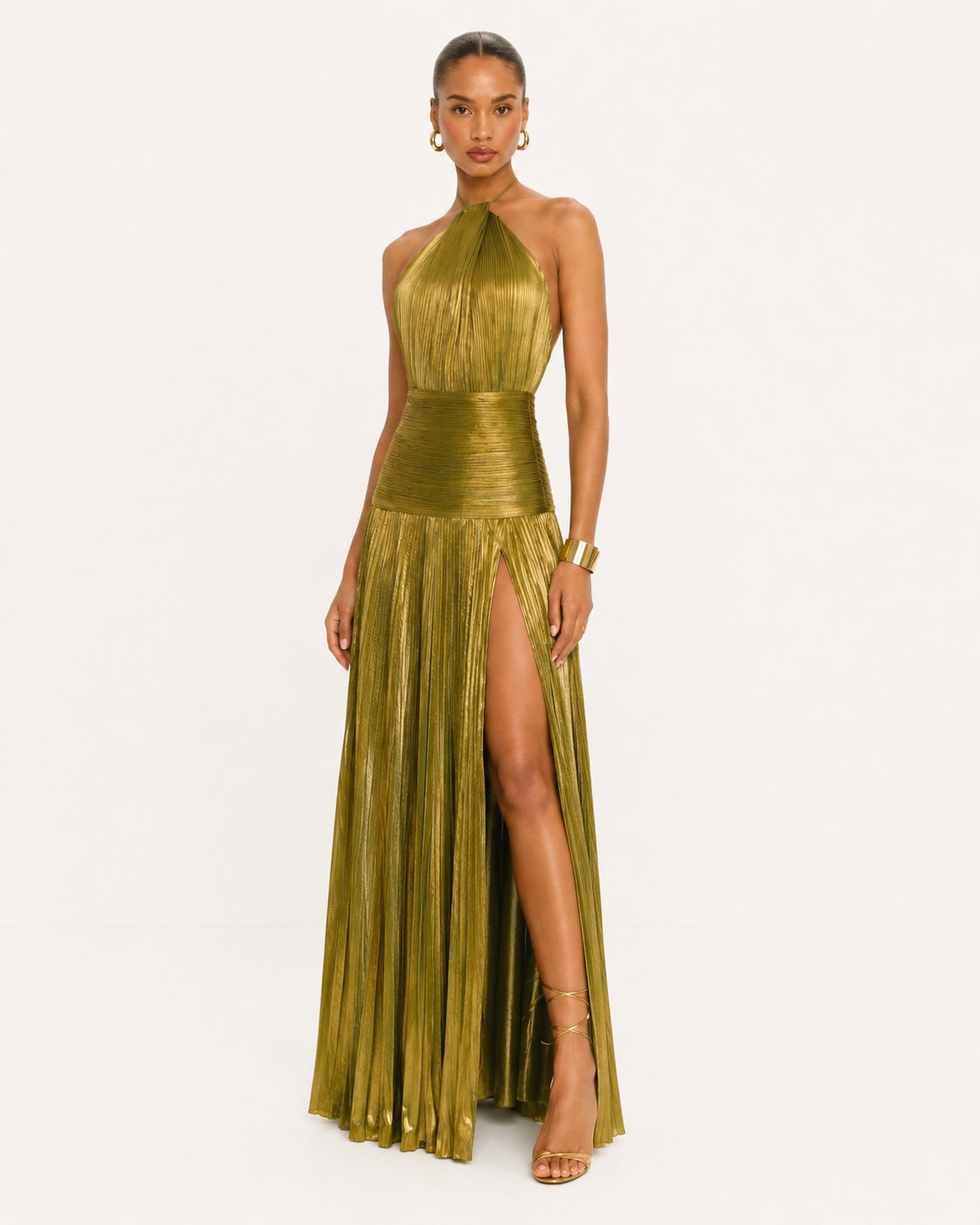 Robe longue dorée avec jupe plissée et ouverture sur la cuisse, associant glamour moderne et sophistication pour les grandes occasions.