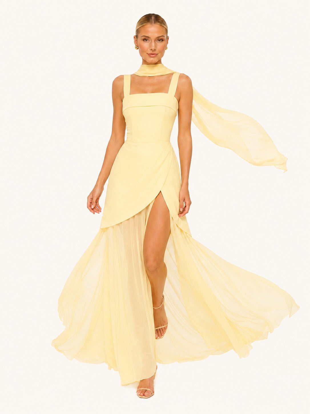 Robe jaune longue en tissu fluide avec voile flottant et fente élégante, créant un mouvement spectaculaire pour une allure glamour et raffinée.