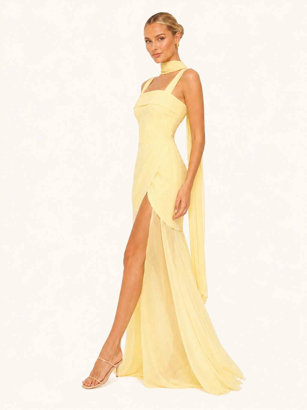 Profil d’une robe longue jaune pastel à coupe près du corps, fente audacieuse et voile aérien, idéale pour mariage, gala ou événement prestigieux.