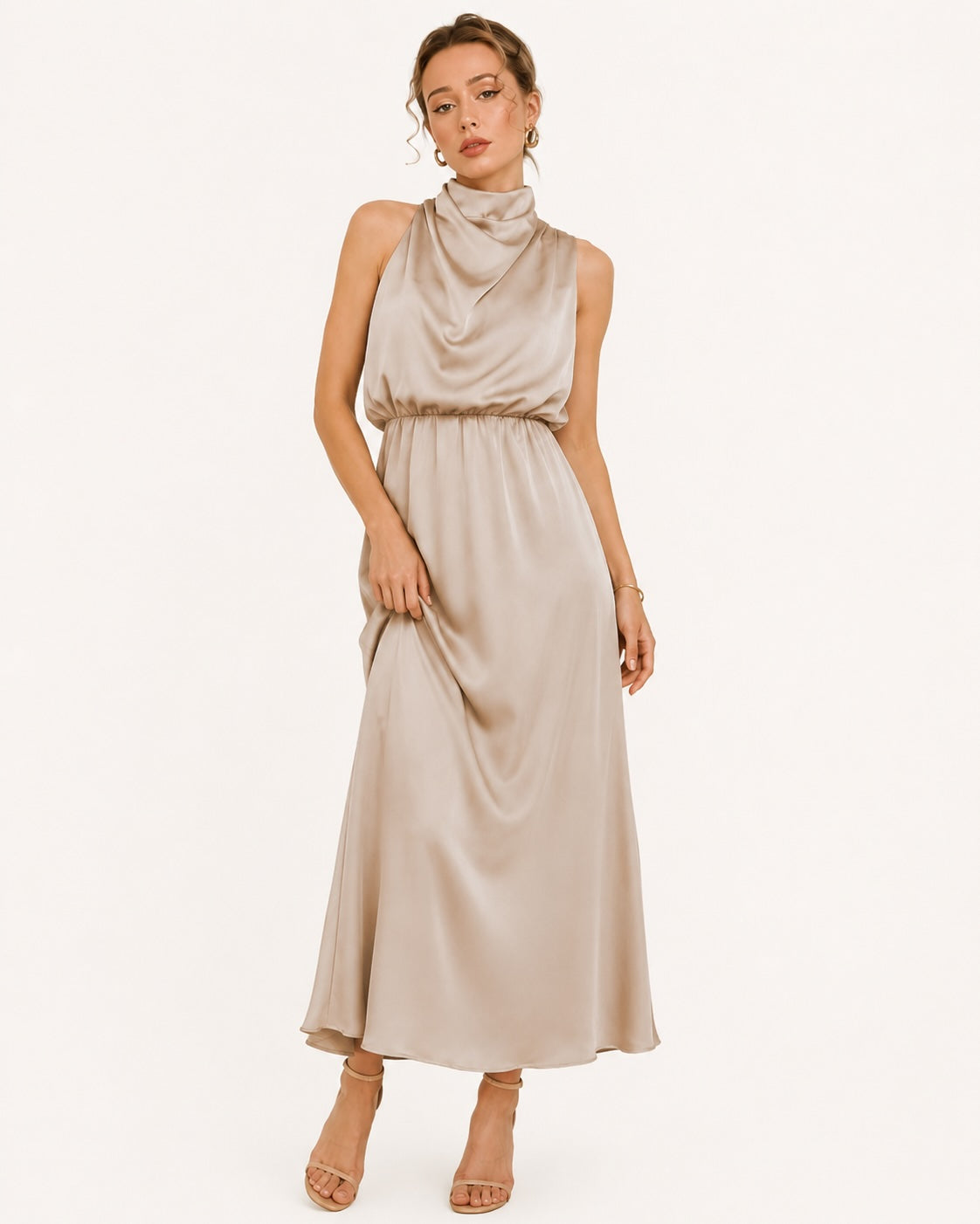 Robe longue satinée beige champagne avec col drapé et taille marquée, parfaite pour une invitée de mariage ou un événement élégant. Vue de face avec mouvement.