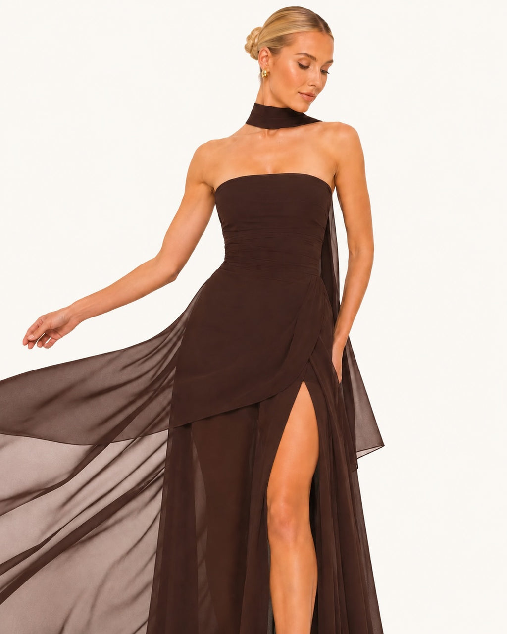 Robe de cérémonie marron avec voile fluide en mouvement, fente glamour et coupe asymétrique, parfaite pour une entrée élégante lors d’un événement prestigieux. Effet mouvement.