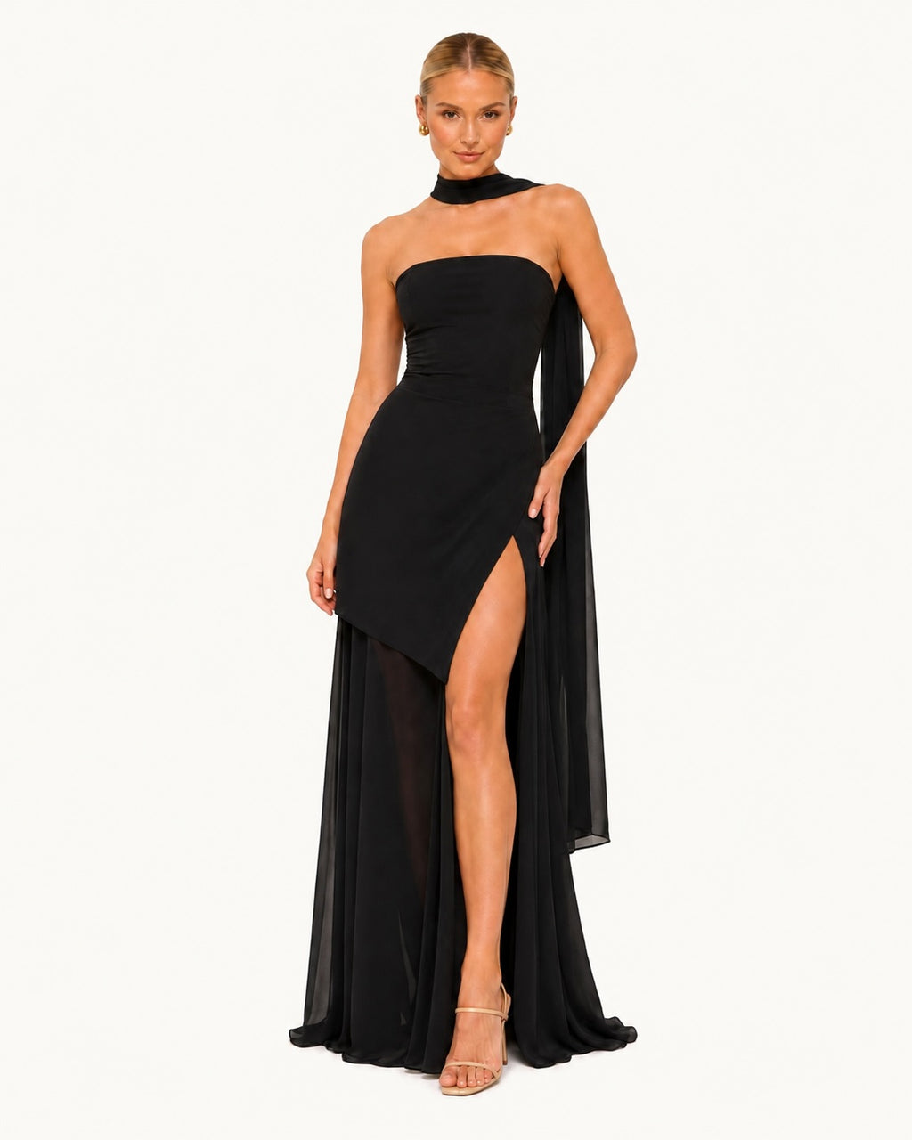 Robe longue noire asymétrique avec fente haute et voile fluide, silhouette glamour idéale pour une soirée élégante, un gala ou une cérémonie prestigieuse. Vue de face.