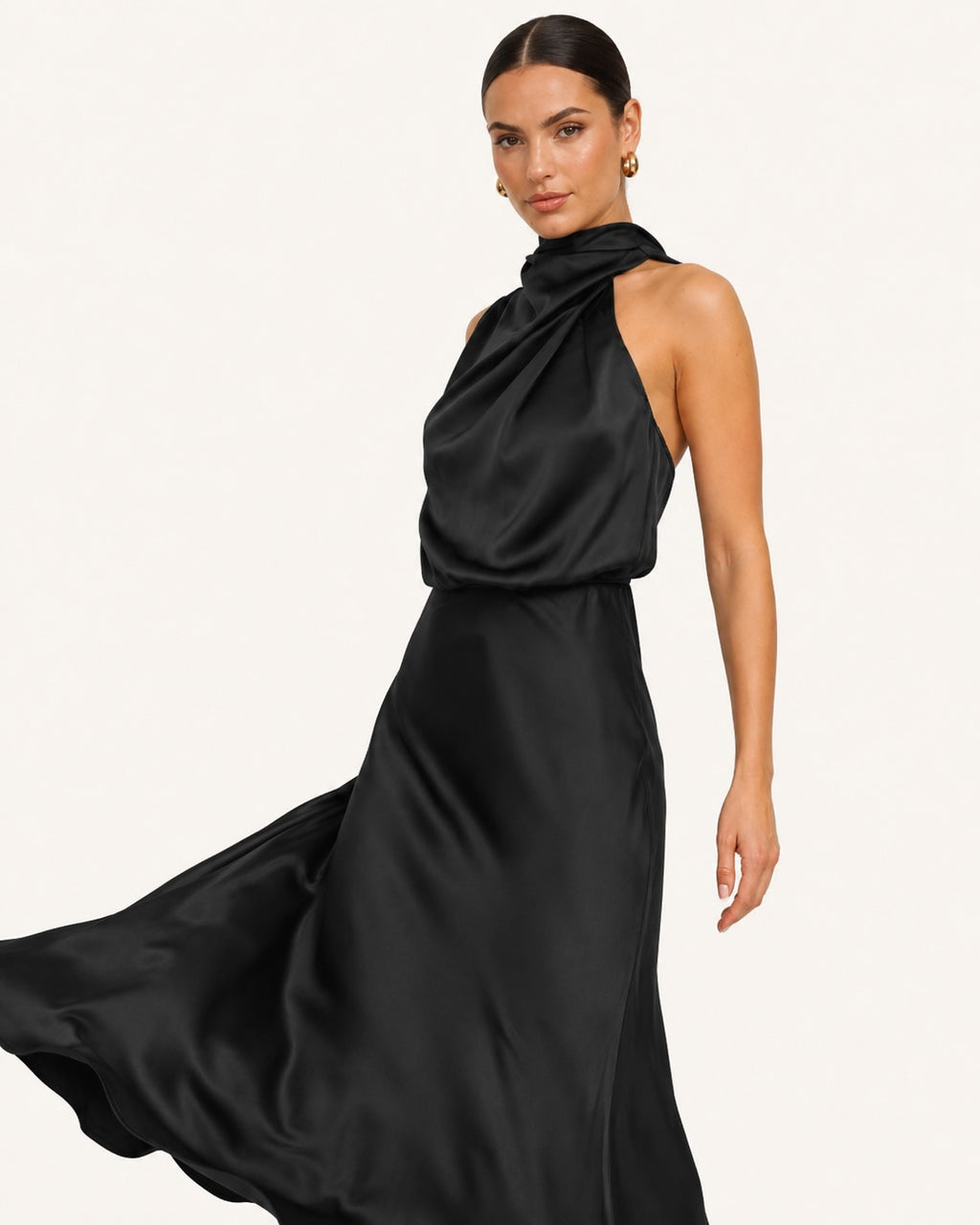 Robe noire satinée fluide avec col montant drapé et jupe évasée en mouvement, parfaite pour une allure sophistiquée lors d’un événement chic.