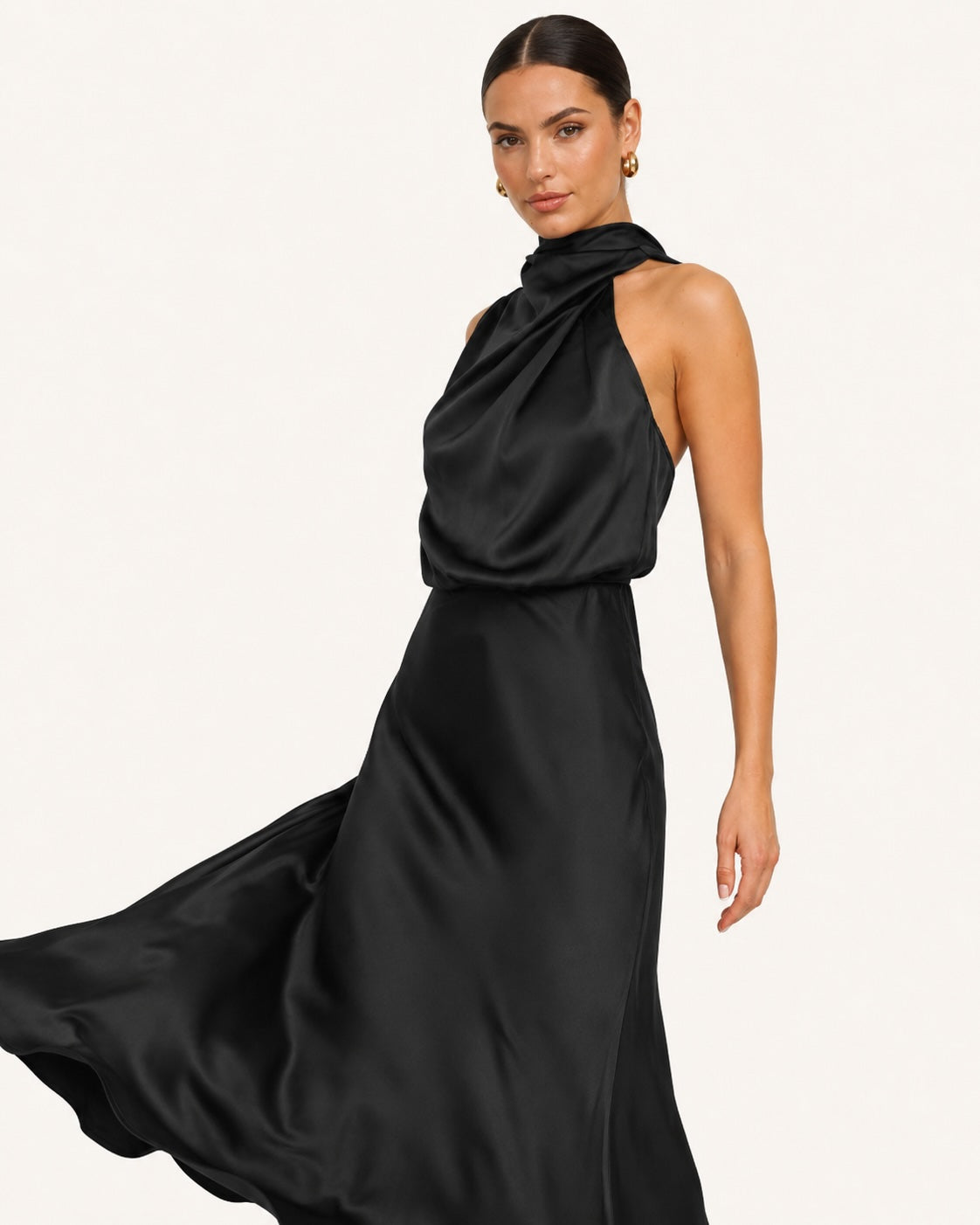 Robe noire satinée fluide avec col montant drapé et jupe évasée en mouvement, parfaite pour une allure sophistiquée lors d’un événement chic.