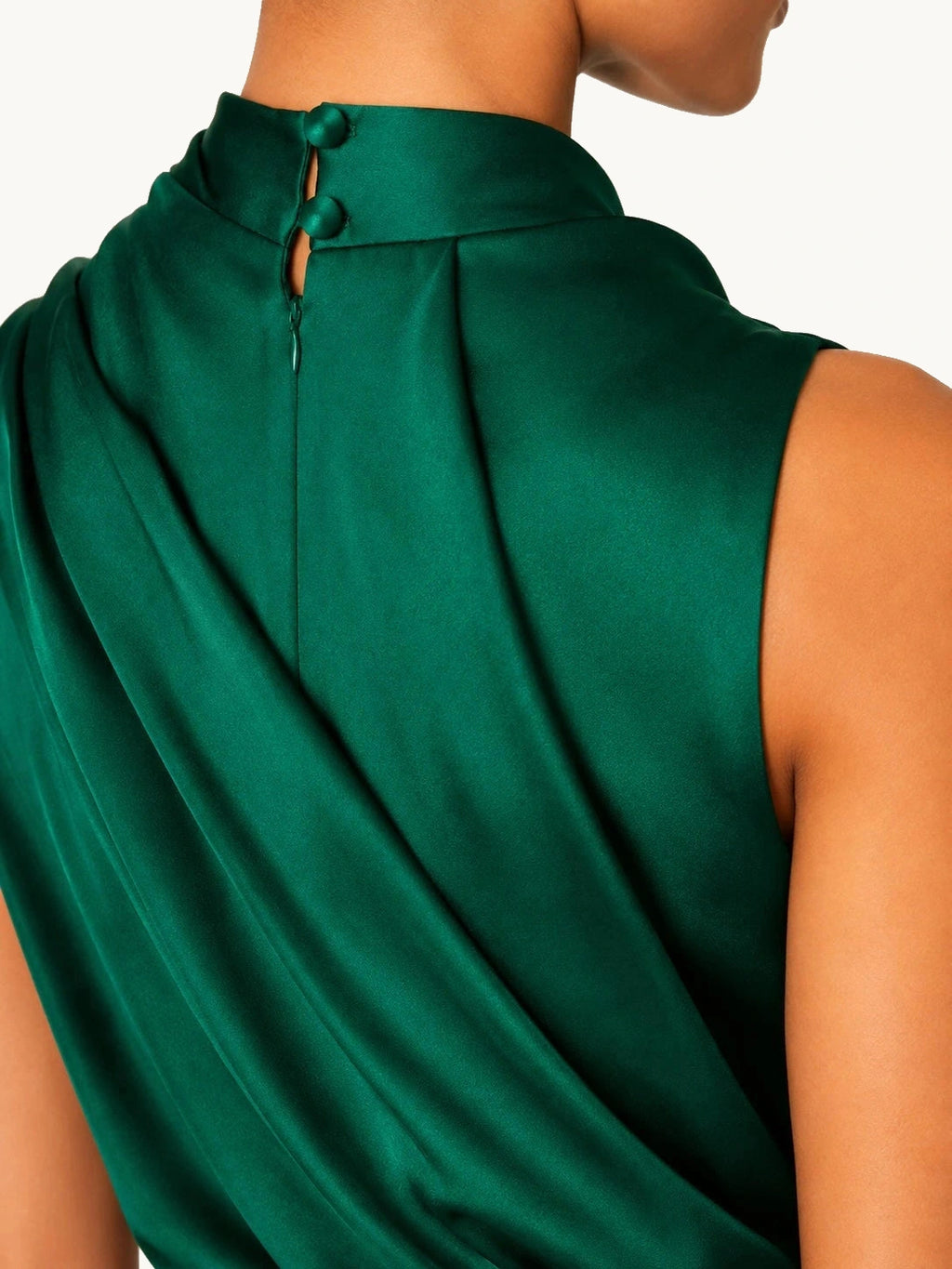 Gros plan sur le col montant drapé et la fermeture boutonnée d’une robe satinée vert émeraude au design raffiné et luxueux.