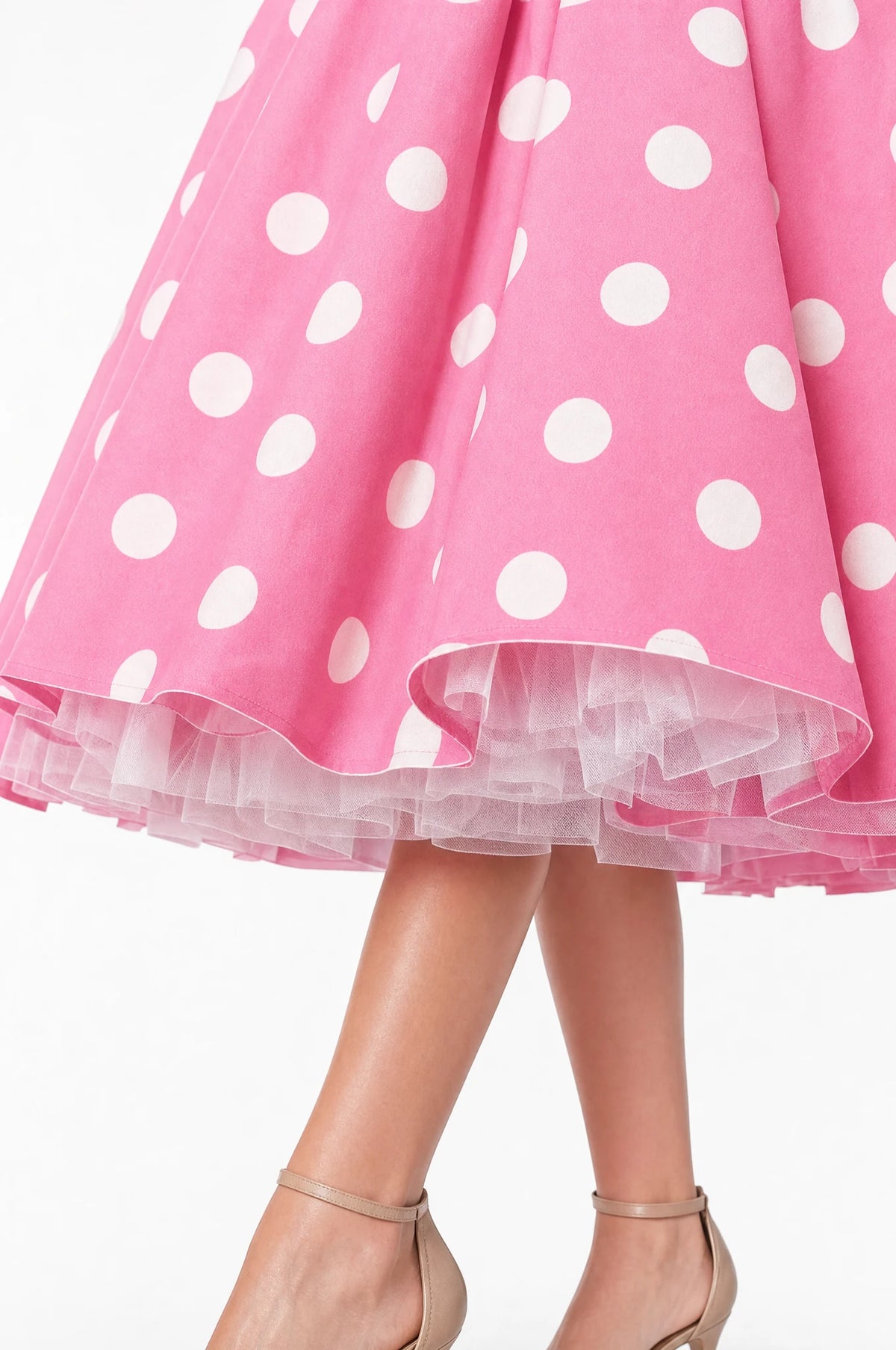Gros plan sur l'ourlet de la robe à pois rose portée par Aude, détail des volants du jupon crinoline blanc en tulle qui dépassent sous la jupe