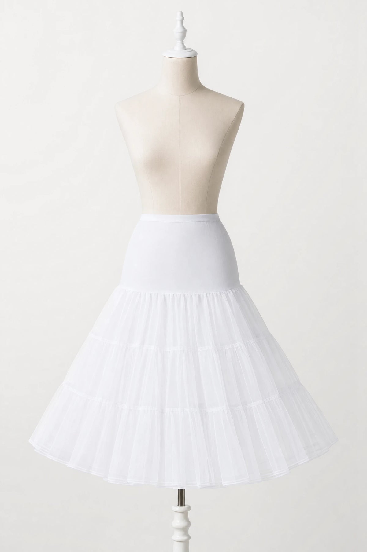 Jupon crinoline blanc vintage à volants seul sur mannequin buste, trois volants superposés en tulle rigide, taille élastiquée, longueur genou