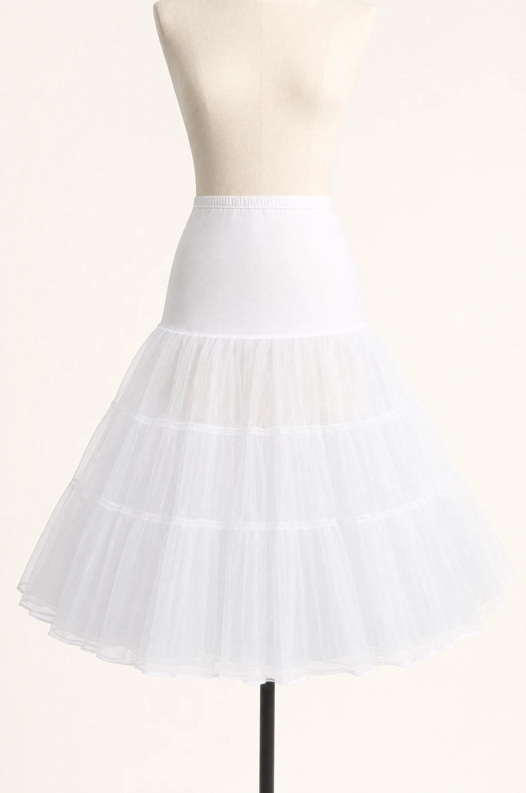 Jupon crinoline blanc vintage à volants seul sur mannequin buste, trois volants superposés en tulle rigide, taille élastiquée, longueur genou
