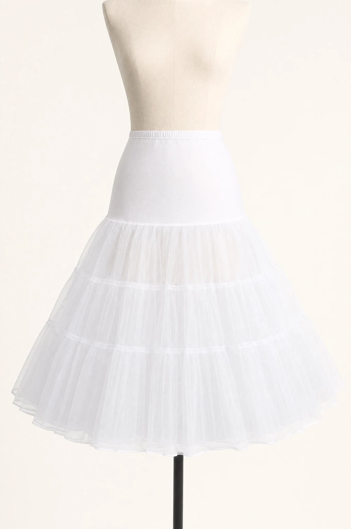 Jupon crinoline blanc vintage à volants seul sur mannequin buste, trois volants superposés en tulle rigide, taille élastiquée, longueur genou