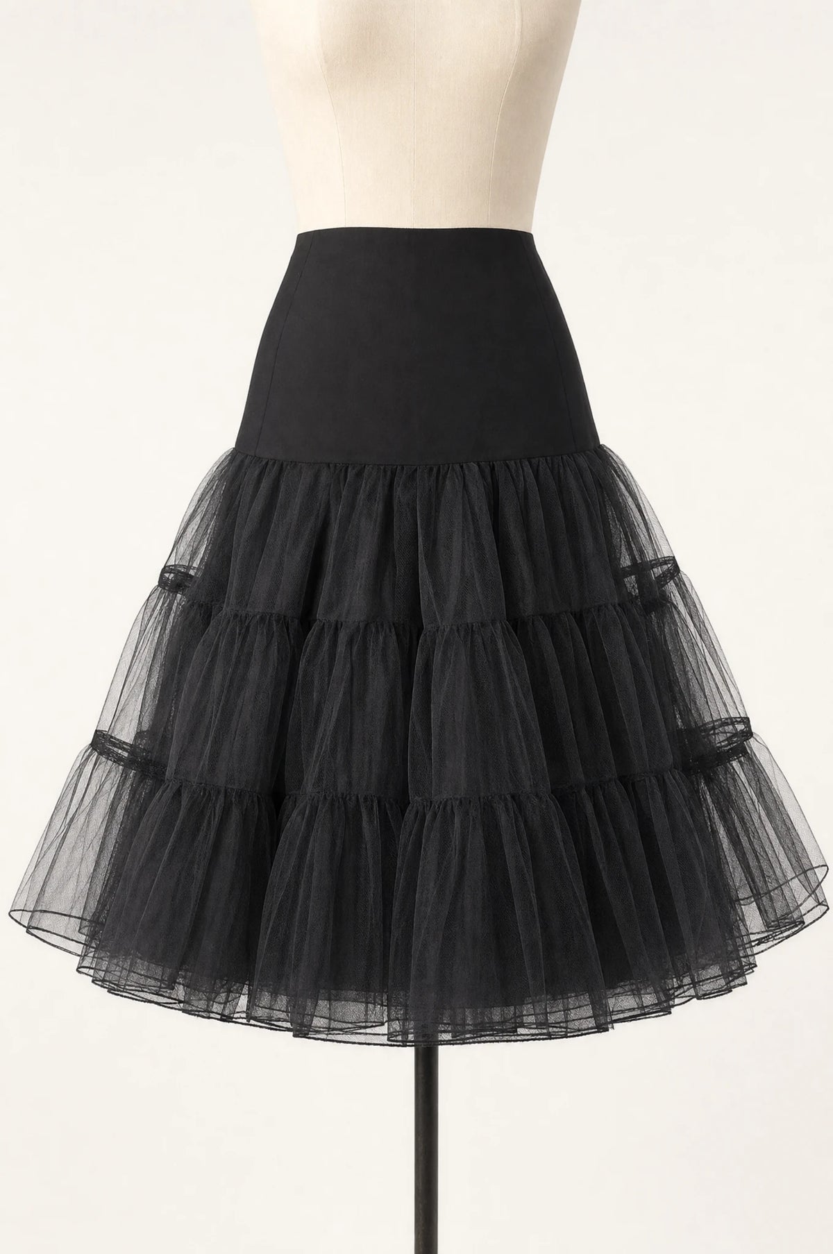 Jupon crinoline noir vintage à volants seul sur mannequin buste, trois volants superposés en tulle rigide, taille élastiquée, longueur genou