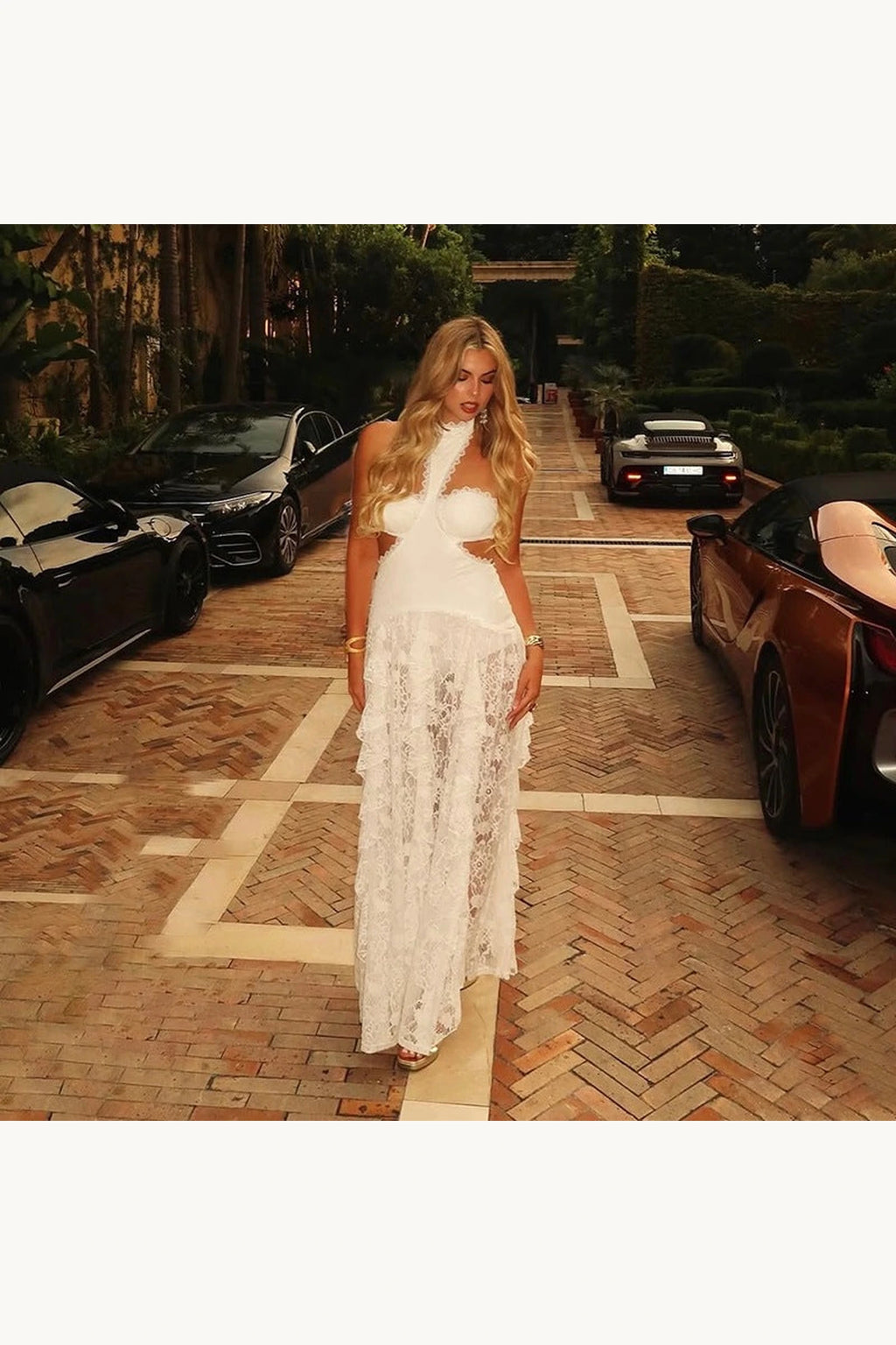 Robe bohème blanche en dentelle Sienna portée en lifestyle soirée, coupe longue, col halter et transparence romantique de la jupe