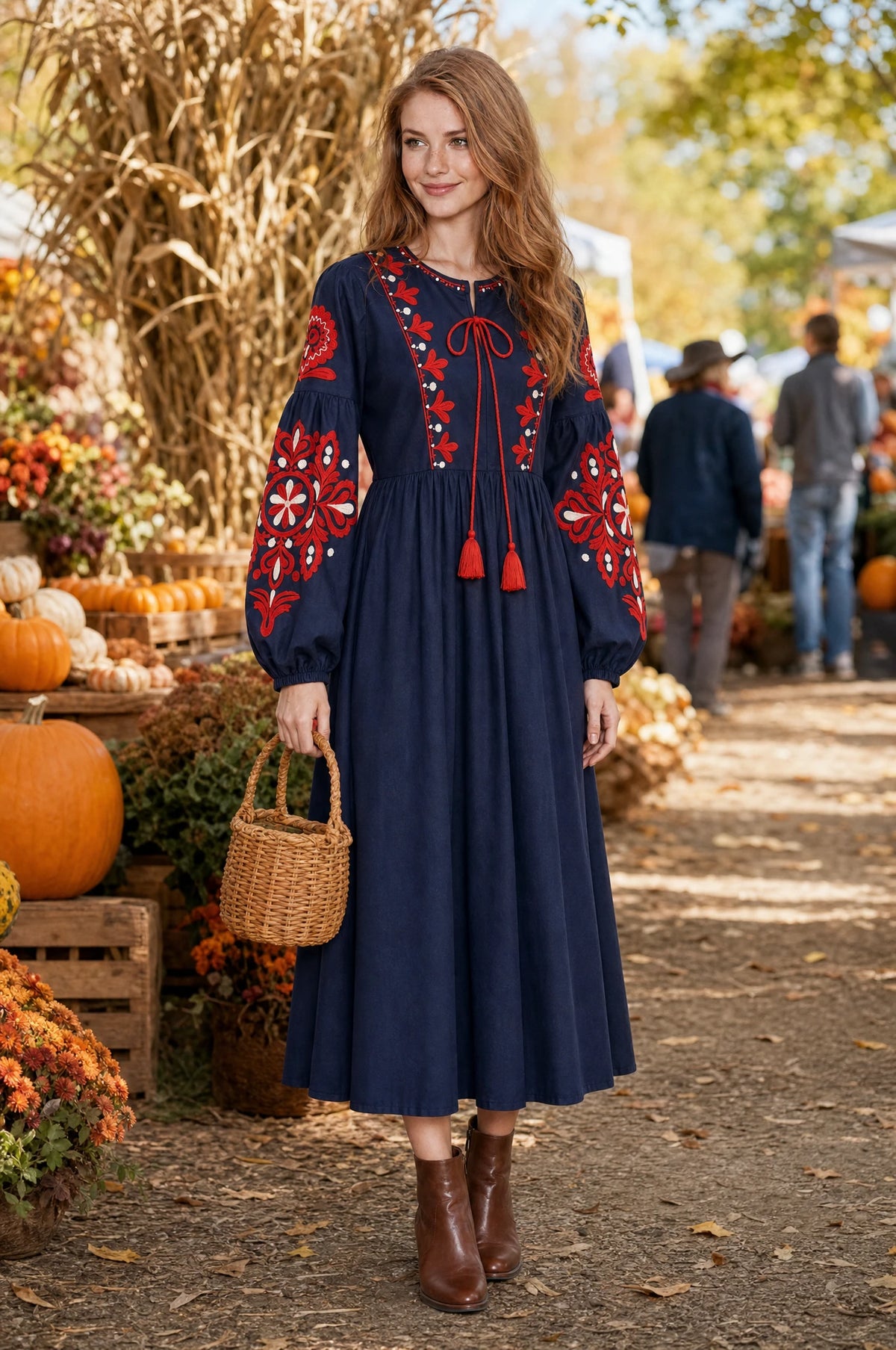 Robe bohème brodée bleu marine Constance portée par Julie dans un marché de producteurs en automne, citrouilles et feuillages dorés, panier en osier, ambiance chaleureuse de saison