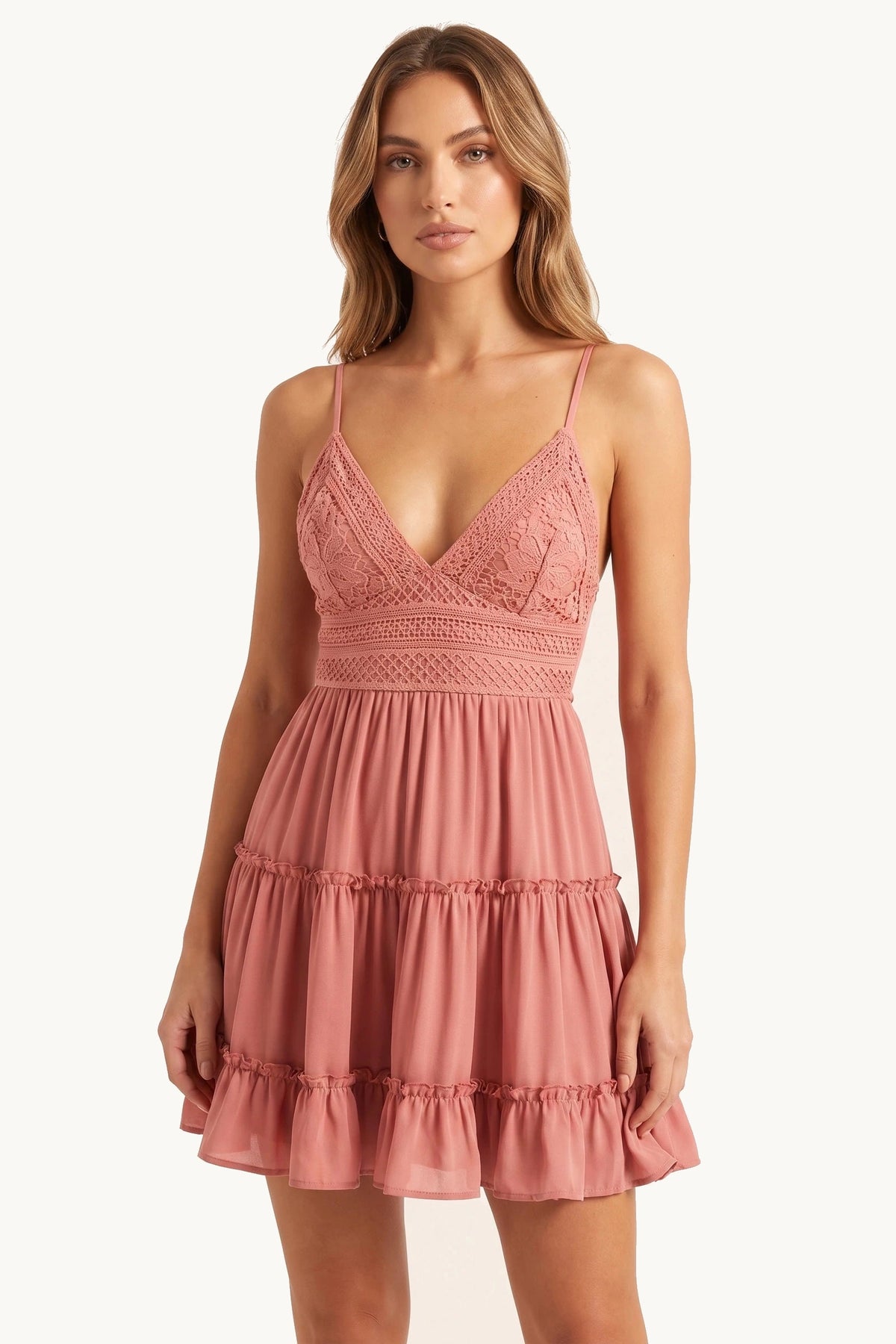 Robe bohème courte Noélie rose portée de face par le Mannequin Élena sur fond neutre clair, bretelles fines, décolleté V profond, buste dentelle crochet et jupe volantée fidèle fournisseur
