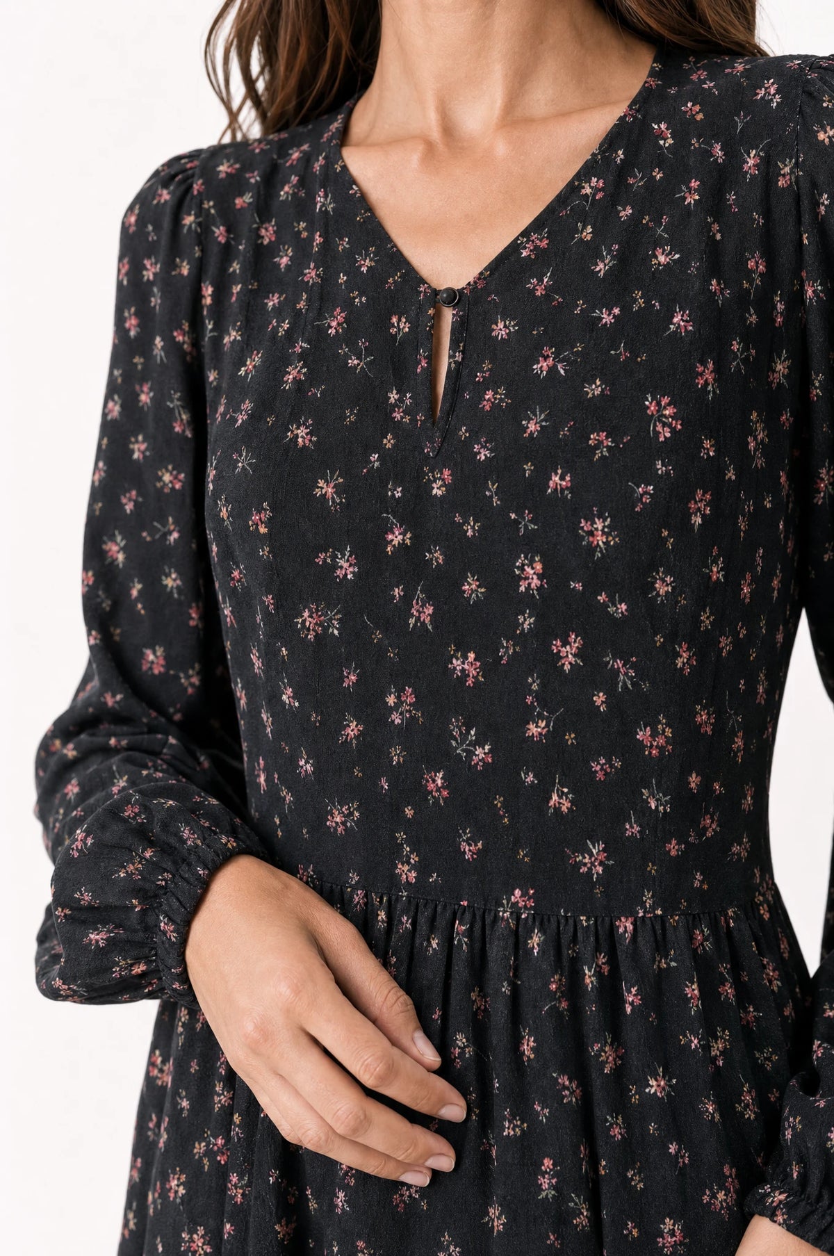 Gros plan sur le col en V pointu à bouton keyhole et la taille marquée de la robe bohème fleurie noire Pauline, détail de l'imprimé floral et du tissu chiffon