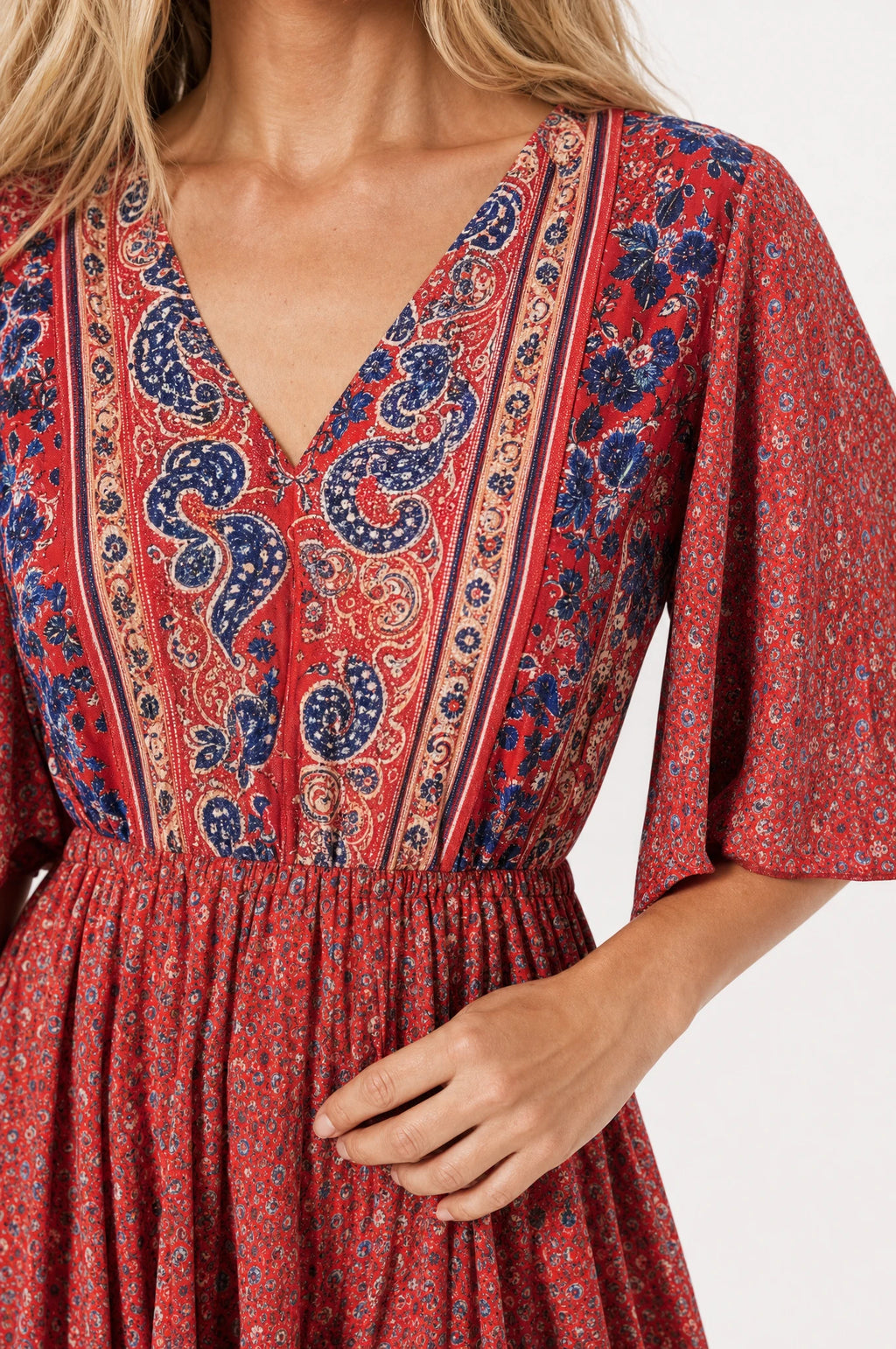 Gros plan sur le décolleté en V bordure paisley bleu marine et la taille élastiquée de la robe bohème fleurie rouge Marguerite, détail de l'imprimé et du tissu coton