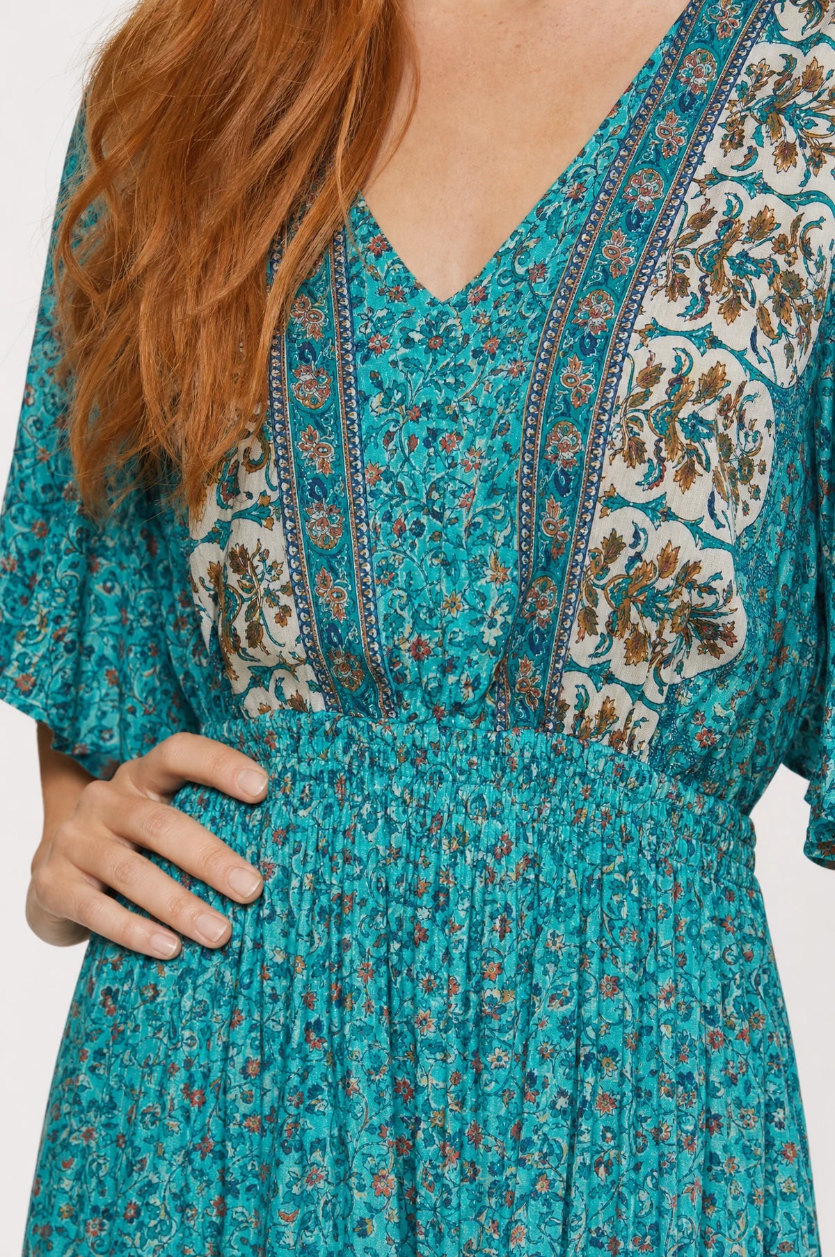 Gros plan sur le décolleté en V bordure paisley et la taille élastiquée de la robe bohème fleurie turquoise Céleste, détail de l'imprimé et du tissu coton