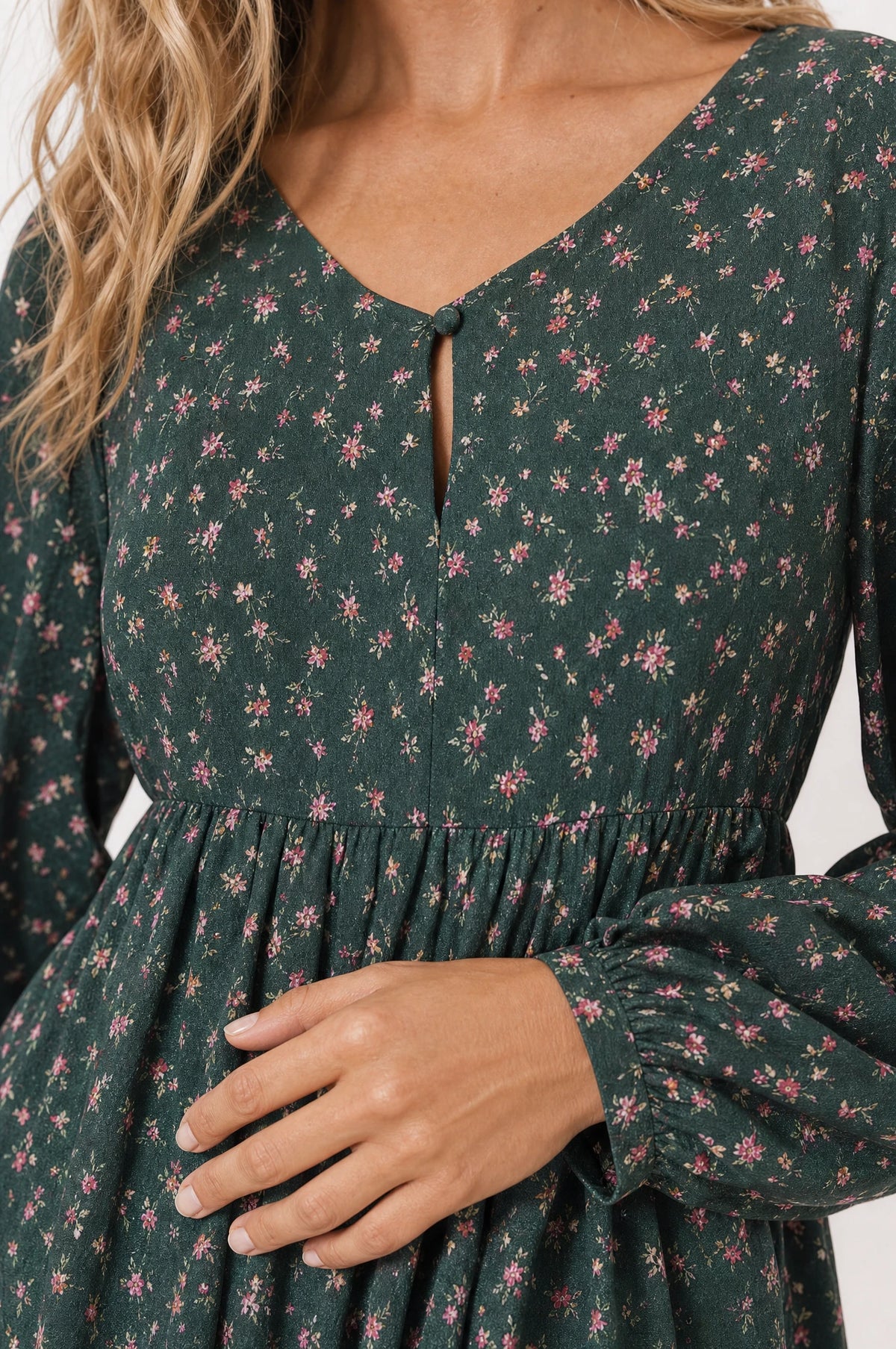 Gros plan sur le col en V à bouton keyhole et la taille marquée de la robe bohème fleurie verte Roxane, détail de l'imprimé floral et du tissu chiffon