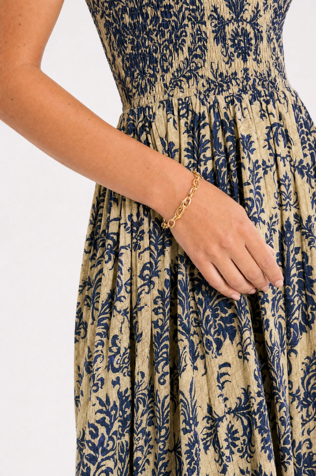 Gros plan sur le bustier smocké élastique et l'imprimé floral damassé bleu profond et doré de la robe bohème Océane, détail du tissu léger et de la taille froncée
