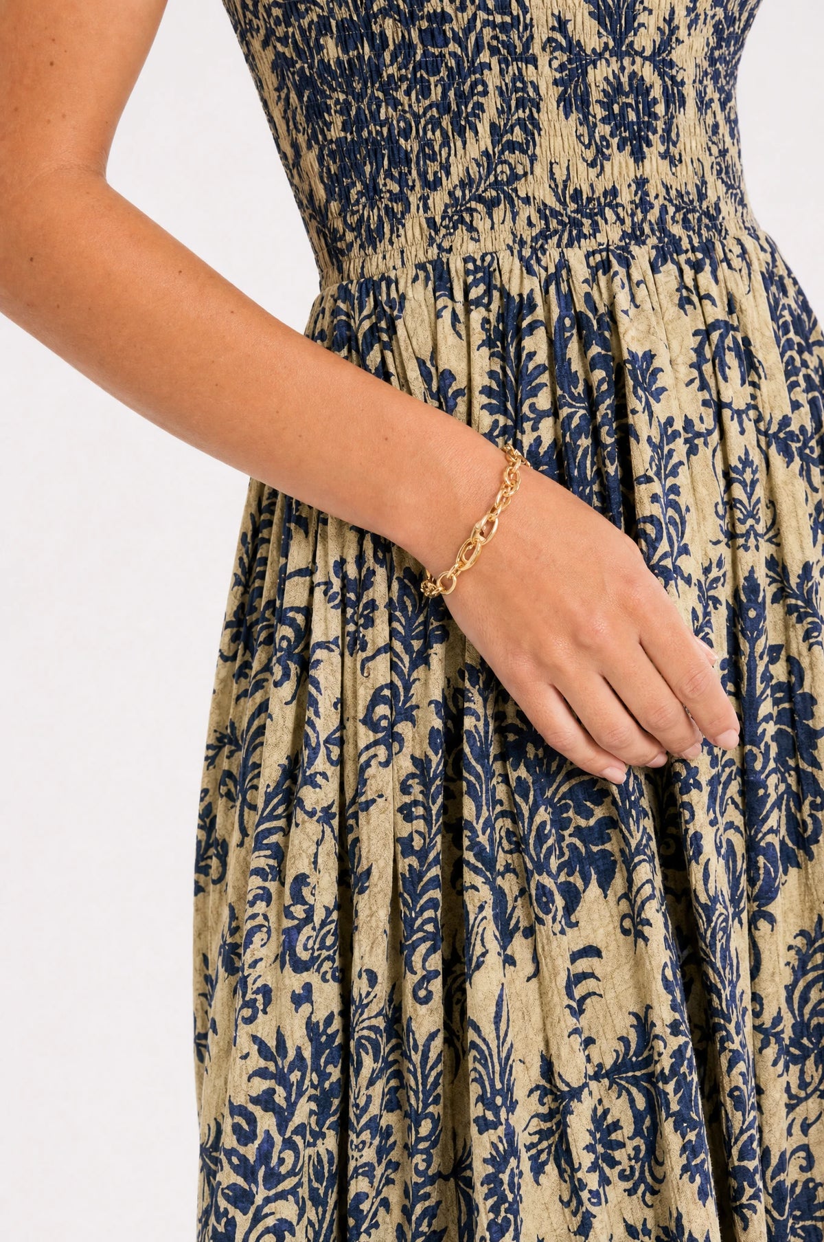 Gros plan sur le bustier smocké élastique et l'imprimé floral damassé bleu profond et doré de la robe bohème Océane, détail du tissu léger et de la taille froncée