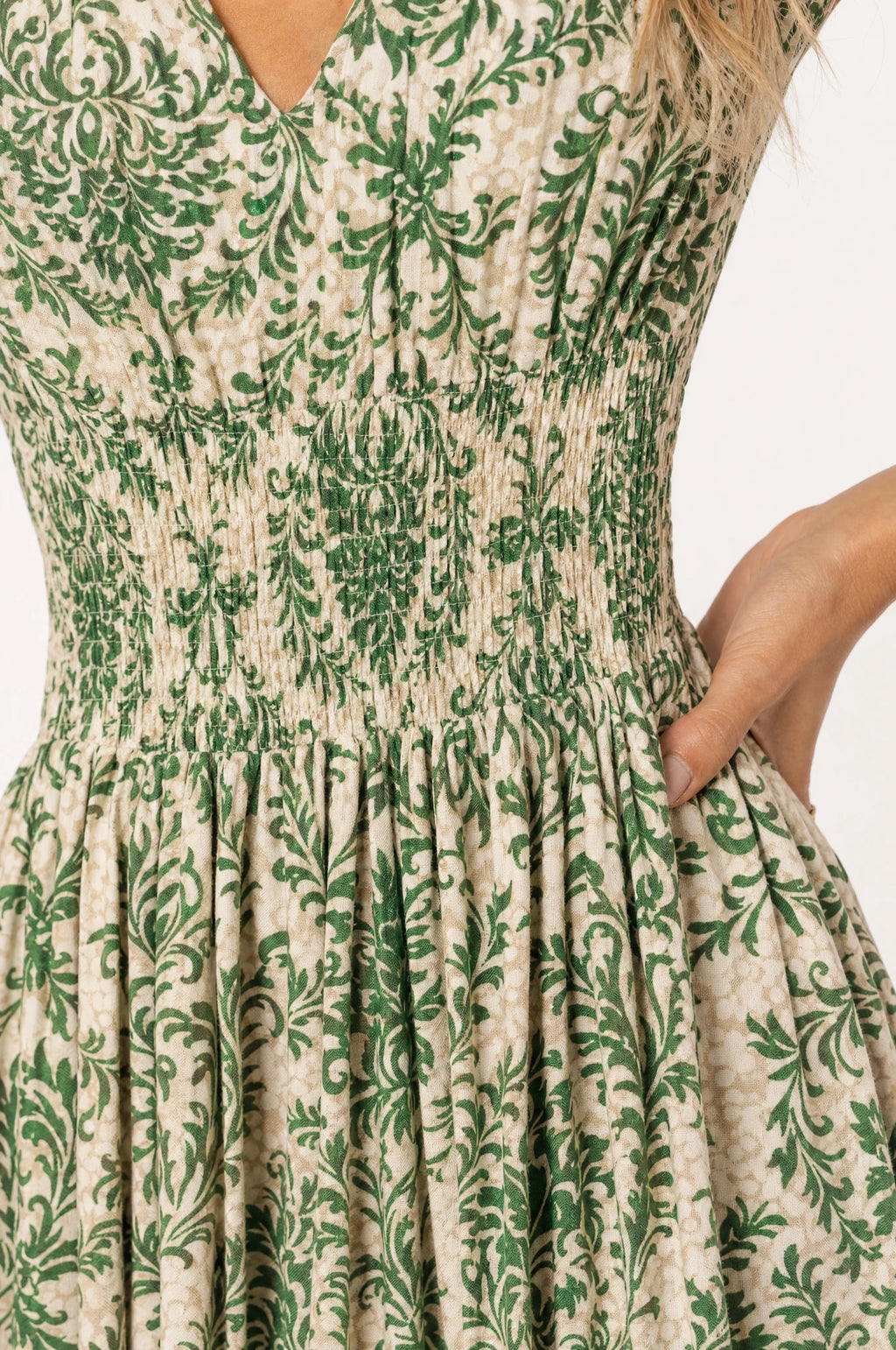 Gros plan sur le bustier smocké élastique et l'imprimé floral damassé vert et écru de la robe bohème Capucine, détail du tissu léger et de la taille froncée
