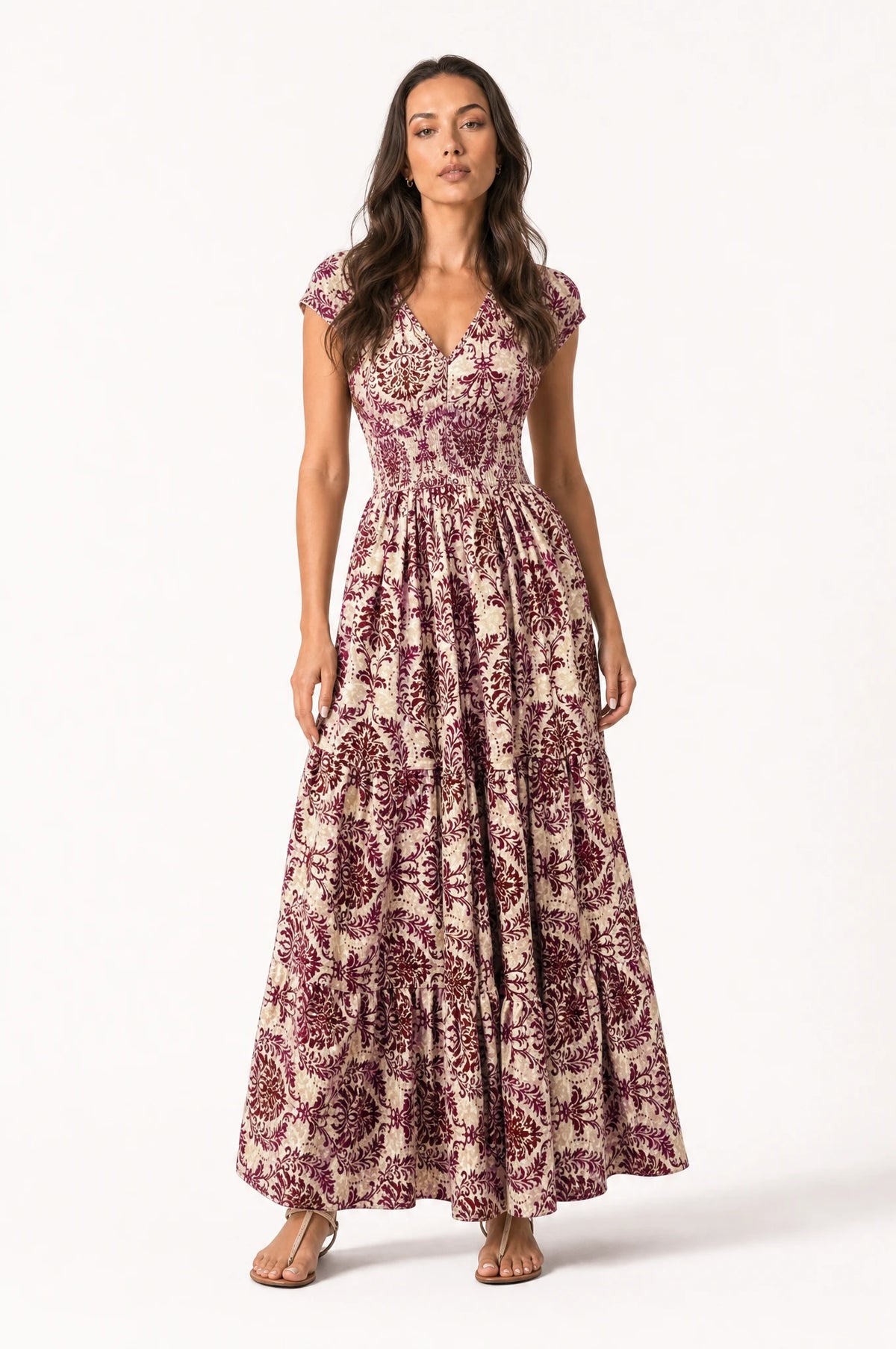 Robe bohème longue fleurie violet Iris portée de face par Nath cheveux détachés, décolleté en V, bustier froncé smocké, manches courtes légèrement bouffantes, jupe évasée à volants imprimé floral violet et prune, tenue idéale pour l'été
