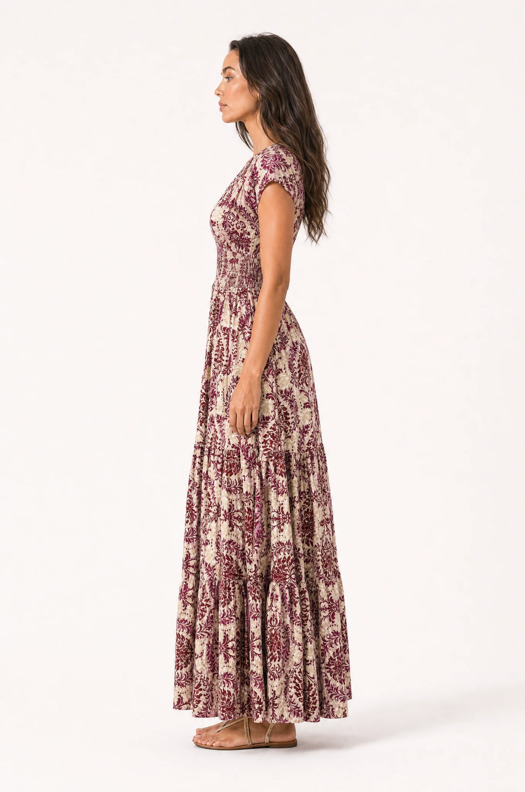 Robe bohème longue fleurie Iris vue de profil portée par Nath cheveux détachés, silhouette fluide et taille froncée, jupe longue à volants jusqu'au sol, coupe ample bohème chic