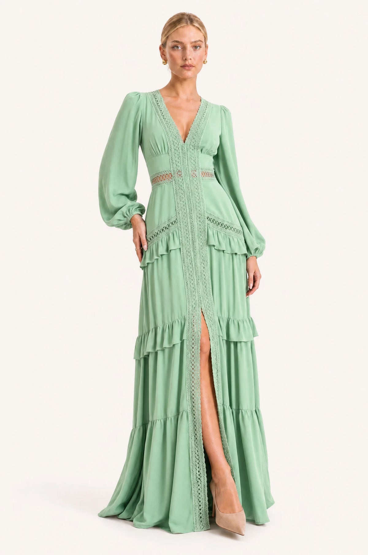 Robe bohème longue vert clair Ondine portée de face par Sophie, décolleté en V profond bordé de dentelle ajourée, manches longues bouffantes, large bande de dentelle à la taille empire, jupe à volants superposés avec fente devant