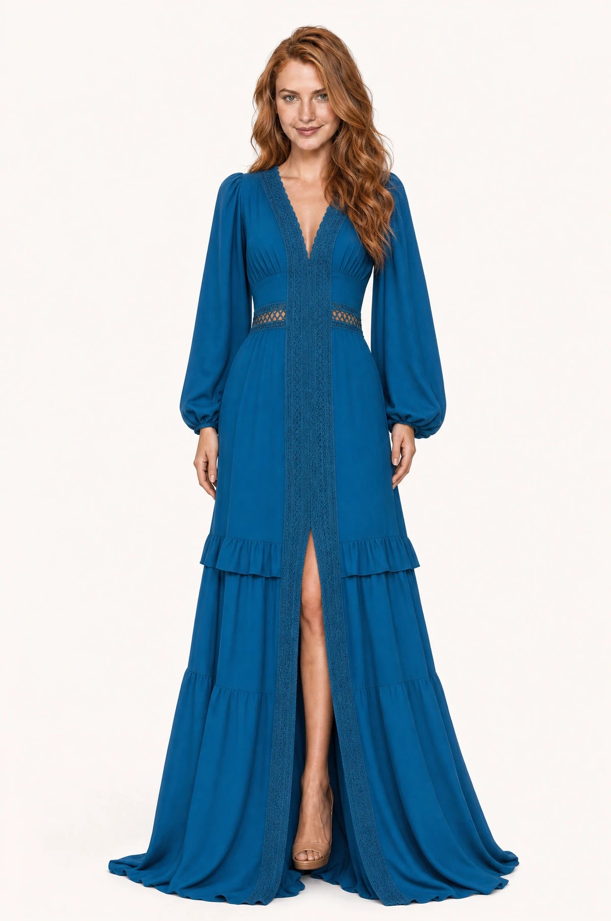 Robe bohème longue bleue Perrine portée de face par Julie cheveux roux ondulés détachés, décolleté en V profond bordé de dentelle, galon central opaque tressé, bande de dentelle ajourée laissant voir la peau à la taille empire, manches longues bouffantes, jupe à volants superposés avec fente devant laissant apparaître la jambe