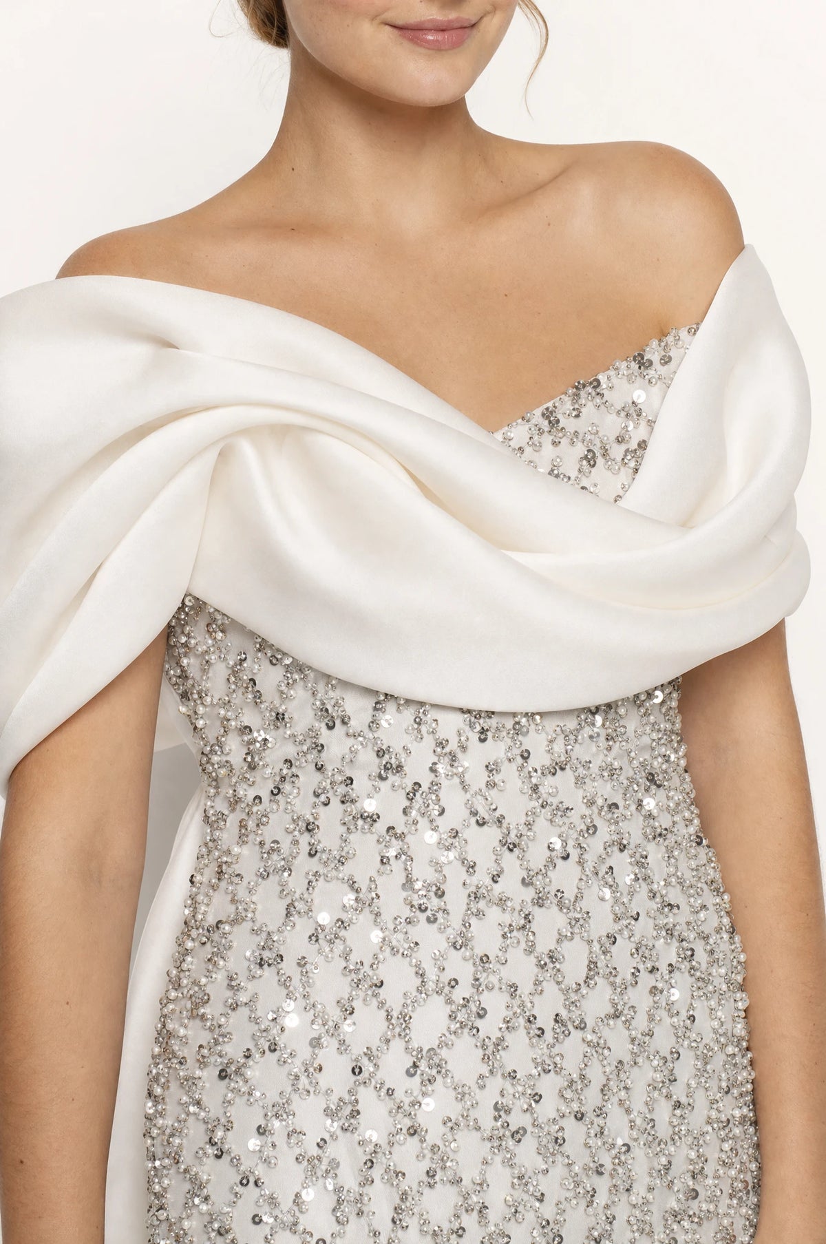 Gros plan sur l'écharpe en satin drapée et torsadée et les sequins brodés du bustier de la robe Albertine, détail du tissu et des perles argentées