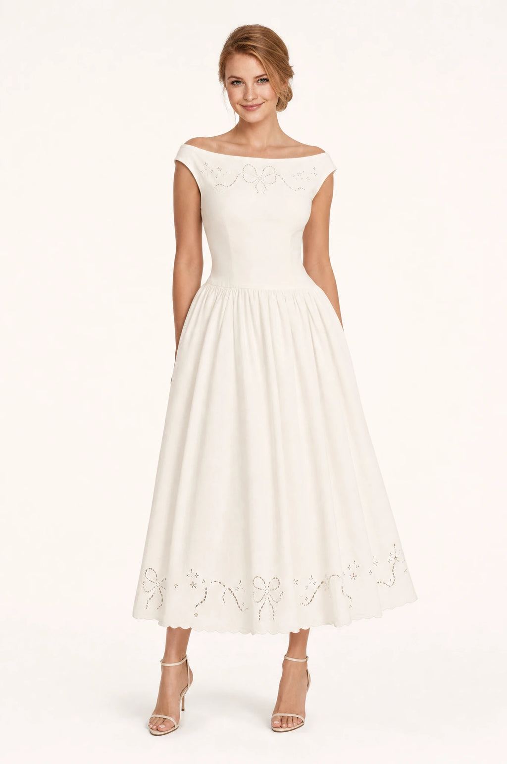 Robe chic blanche Blanche portée de face par Julie chignon bas sleek, décolleté bateau, manches courtes, broderie ajourée façon nœud sur l'empiècement, jupe midi ample cheville
