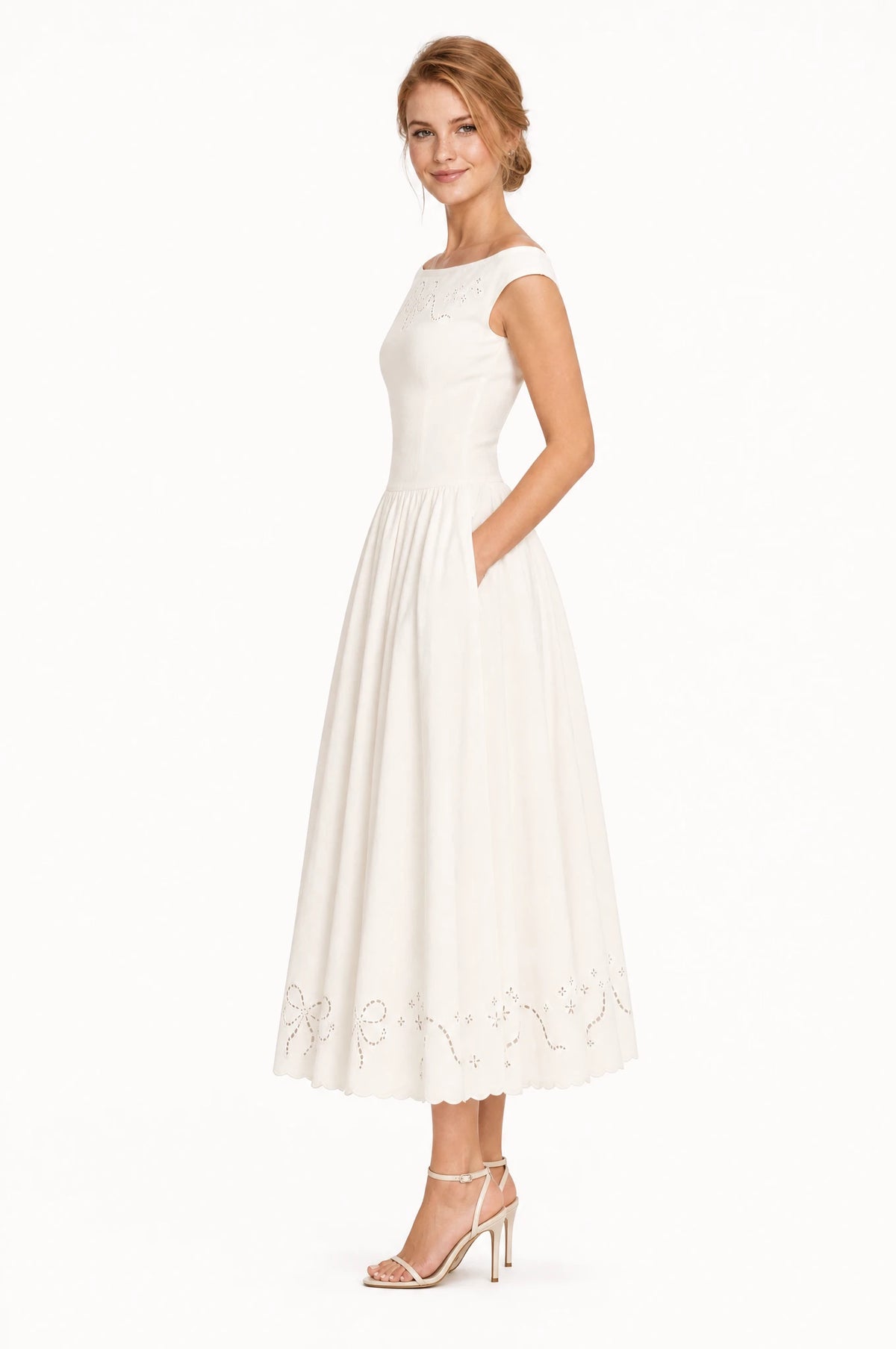 Robe chic blanche Blanche vue de profil portée par Julie, taille cintrée, jupe midi ample avec broderie ajourée à l'ourlet