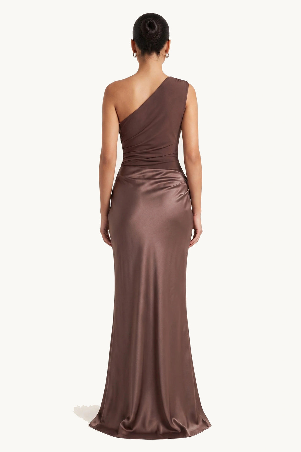 Robe chic longue Jade marron portée de dos sur fond neutre clair, dos asymétrique, pan sur une épaule et jupe satinée fluide
