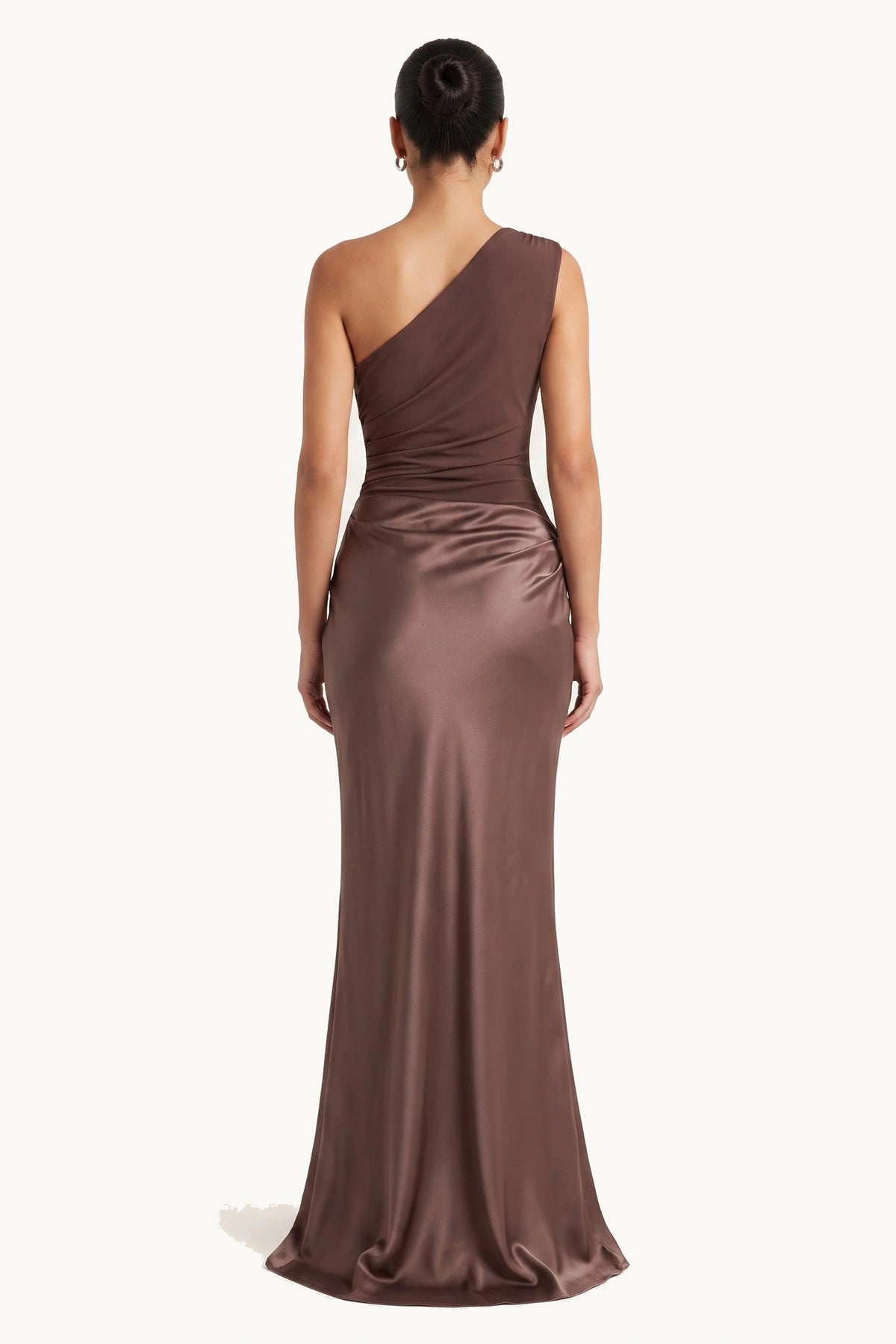 Robe chic longue Jade marron portée de dos sur fond neutre clair, dos asymétrique, pan sur une épaule et jupe satinée fluide