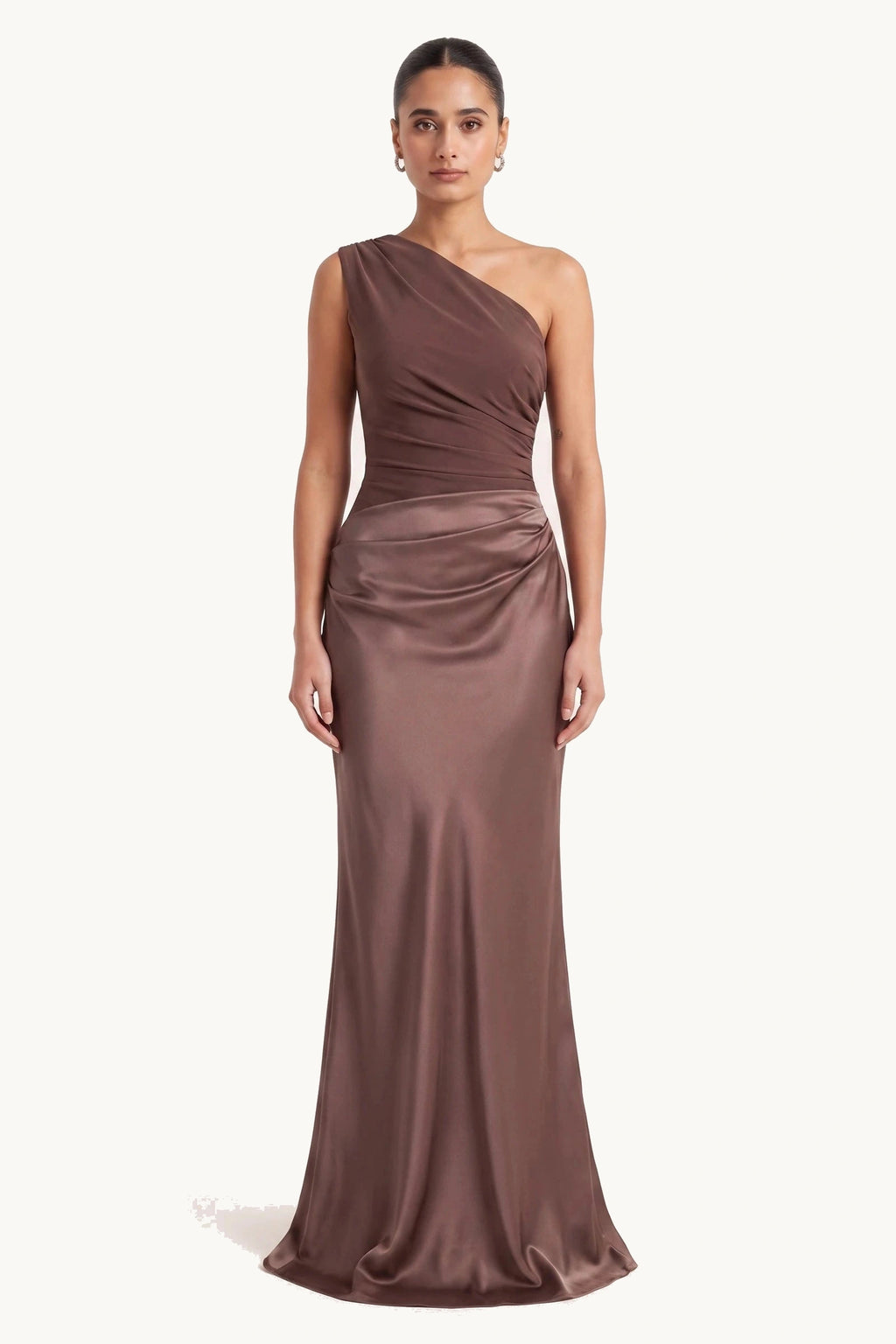 Robe chic longue Jade marron portée de face sur fond neutre clair, haut et jupe en même satin marron, épaule asymétrique, drapé à la taille et silhouette élégante