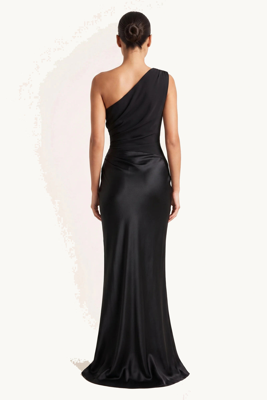 Robe chic longue Jade noire portée de dos sur fond neutre clair, dos asymétrique et jupe longue satinée fidèle fournisseur