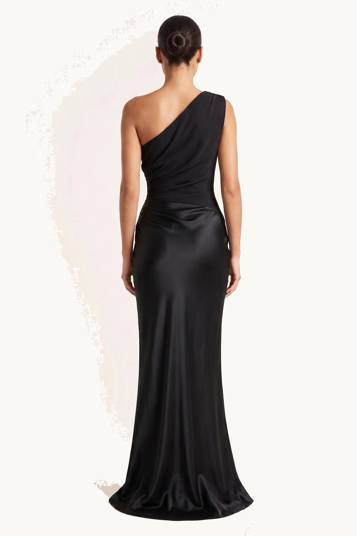 Robe chic longue Jade noire portée de dos sur fond neutre clair, dos asymétrique et jupe longue satinée fidèle fournisseur