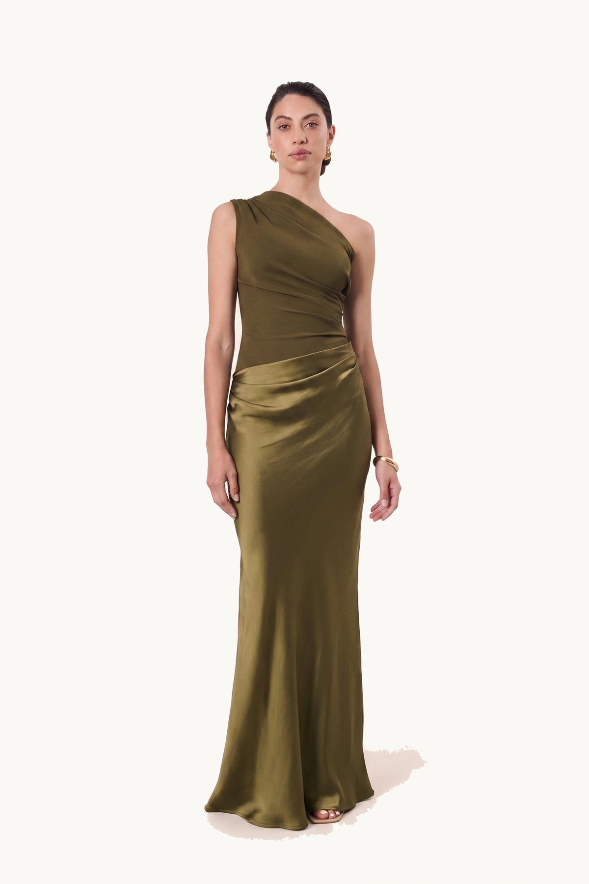 Robe chic longue Jade vert olive portée de face sur fond neutre clair, haut et jupe en même satin vert olive, épaule asymétrique et silhouette habillée