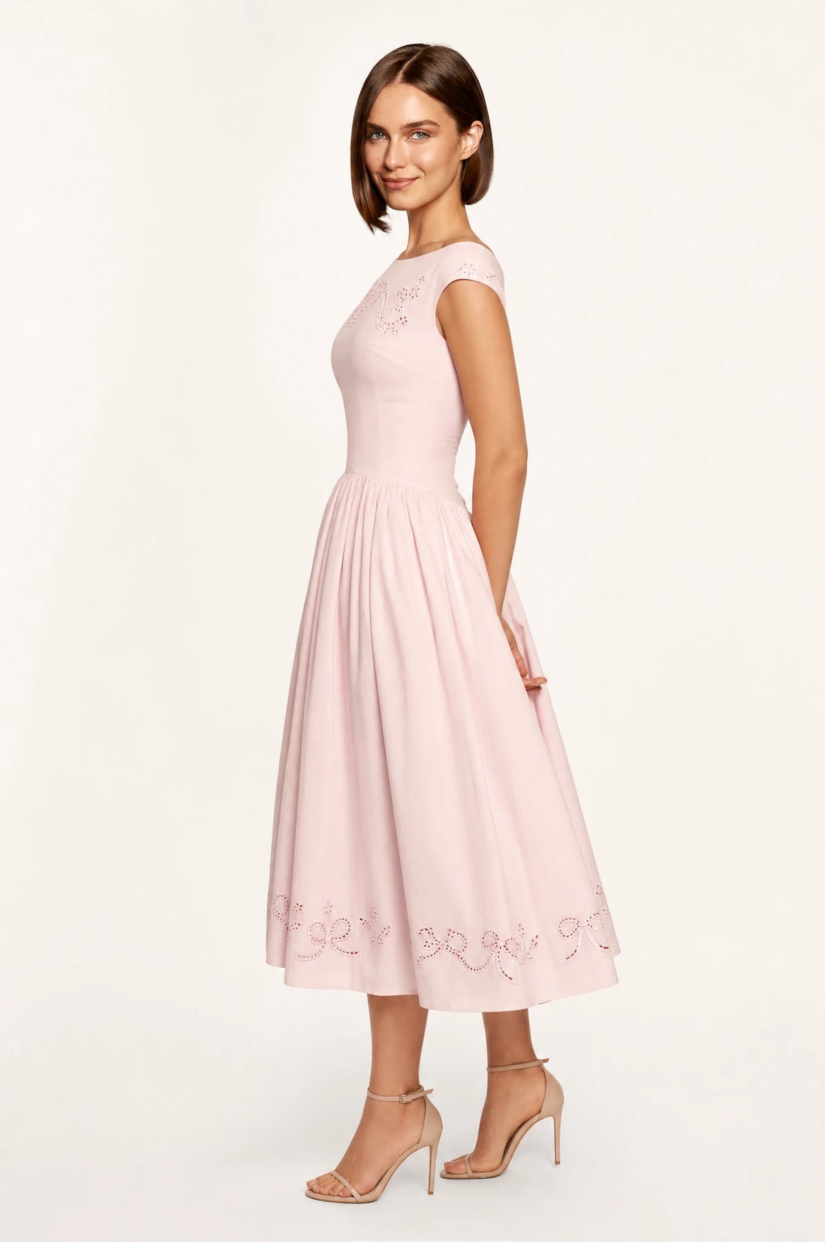 Dos de la robe chic rose brodée Anaïs portée par Élodie, encolure bateau dégagée de dos, taille cintrée, jupe midi évasée jusqu'au mollet