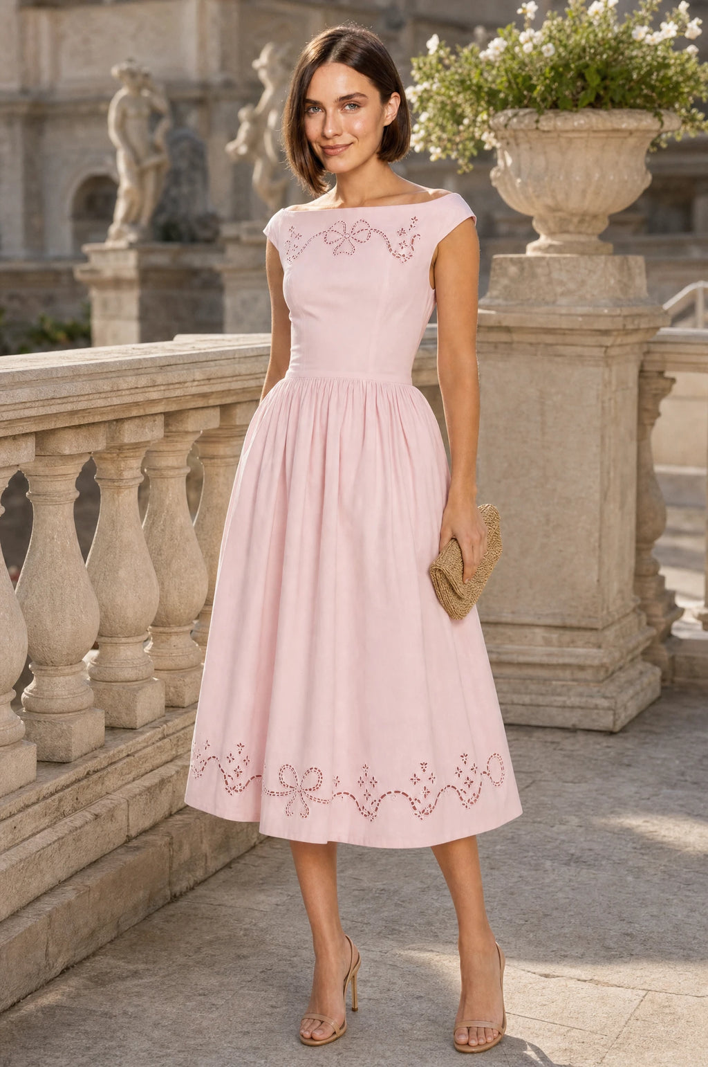 Robe chic rose brodée Anaïs portée par Élodie lors d'une réception de mariage en plein air au crépuscule, guirlande lumineuse et tables fleuries, pochette en raphia à la main, ambiance élégante