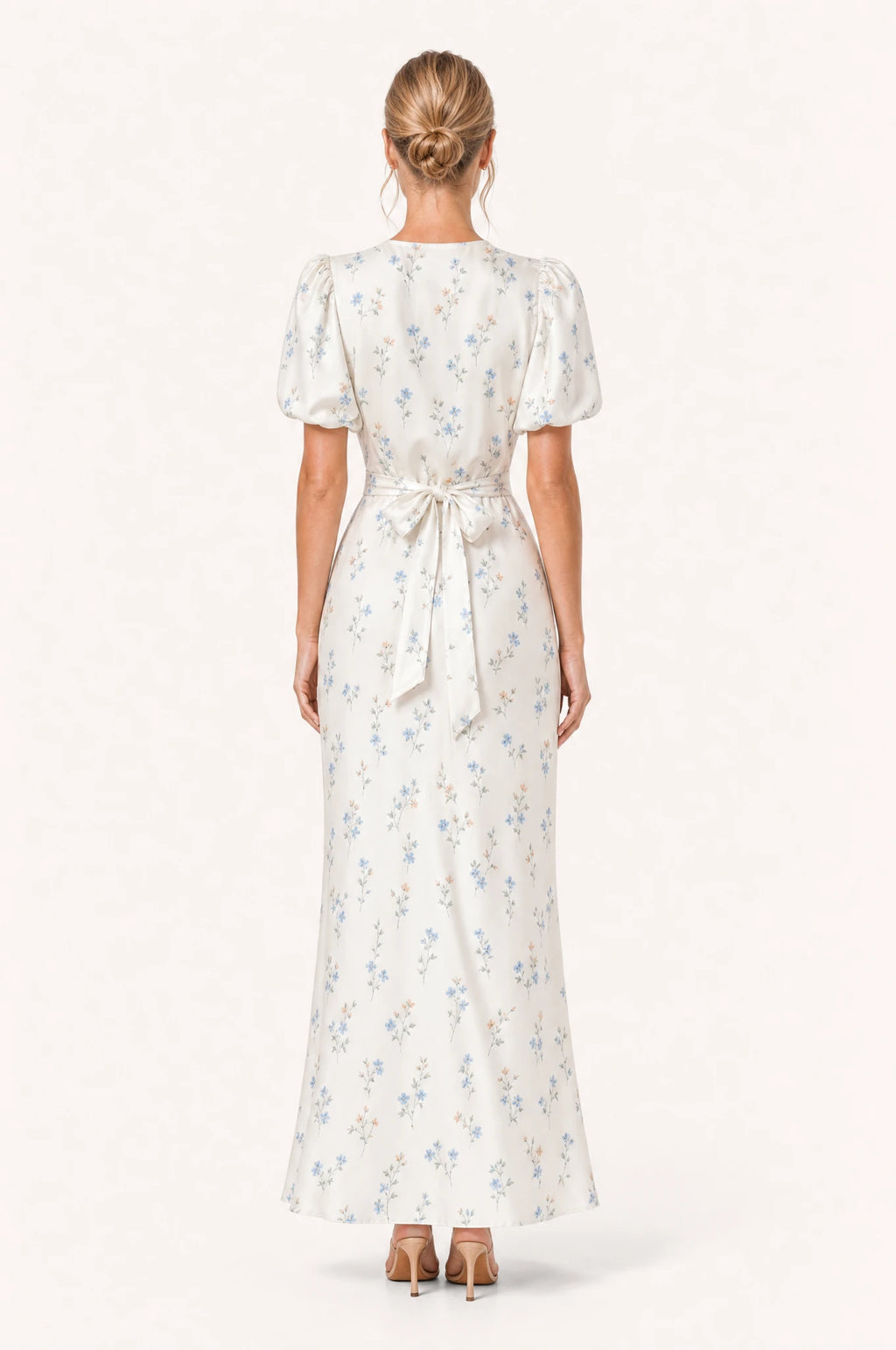 Dos de la robe cocktail bleue fleurie Bérénice portée par Aude, nœud noué à la taille dans le dos, manches courtes bouffantes, jupe fourreau longueur cheville