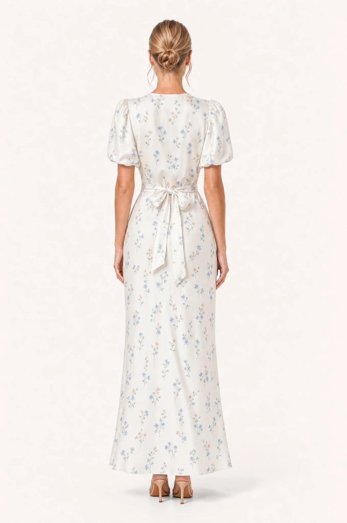 Dos de la robe cocktail bleue fleurie Bérénice portée par Aude, nœud noué à la taille dans le dos, manches courtes bouffantes, jupe fourreau longueur cheville