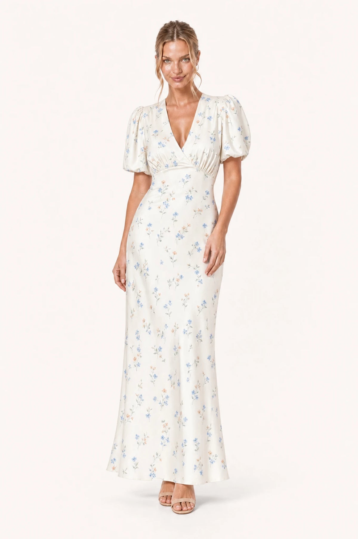 Robe cocktail bleue fleurie Bérénice portée de face par Aude chignon bas sleek, décolleté en V profond façon cache-cœur, manches courtes bouffantes satinées, taille marquée, jupe fourreau longueur cheville légèrement évasée
