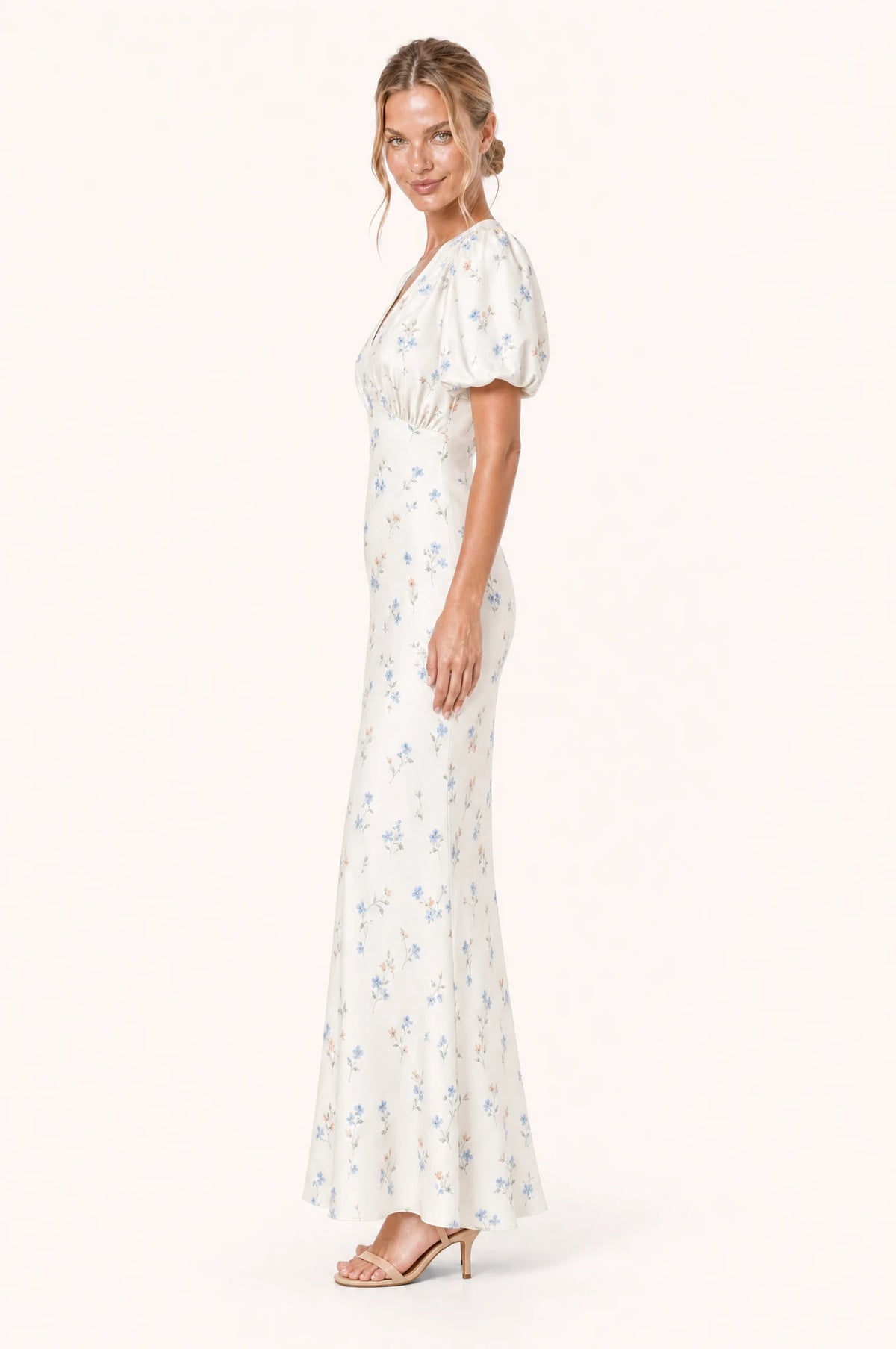 Robe cocktail bleue fleurie Bérénice vue de profil portée par Aude, taille marquée, jupe fourreau longueur cheville légèrement évasée à l'ourlet