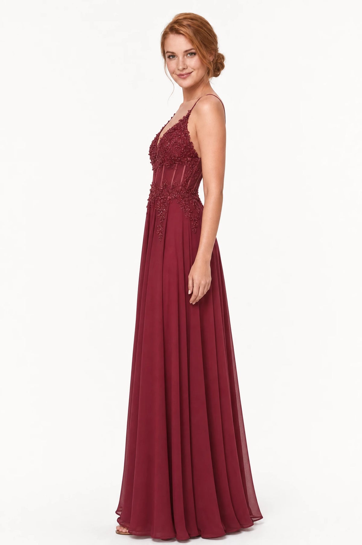 Robe cocktail bordeaux Valentine vue de profil portée par Julie chignon bas, silhouette évasée en A, bustier structuré en dentelle perlée, jupe longue en mousseline fluide