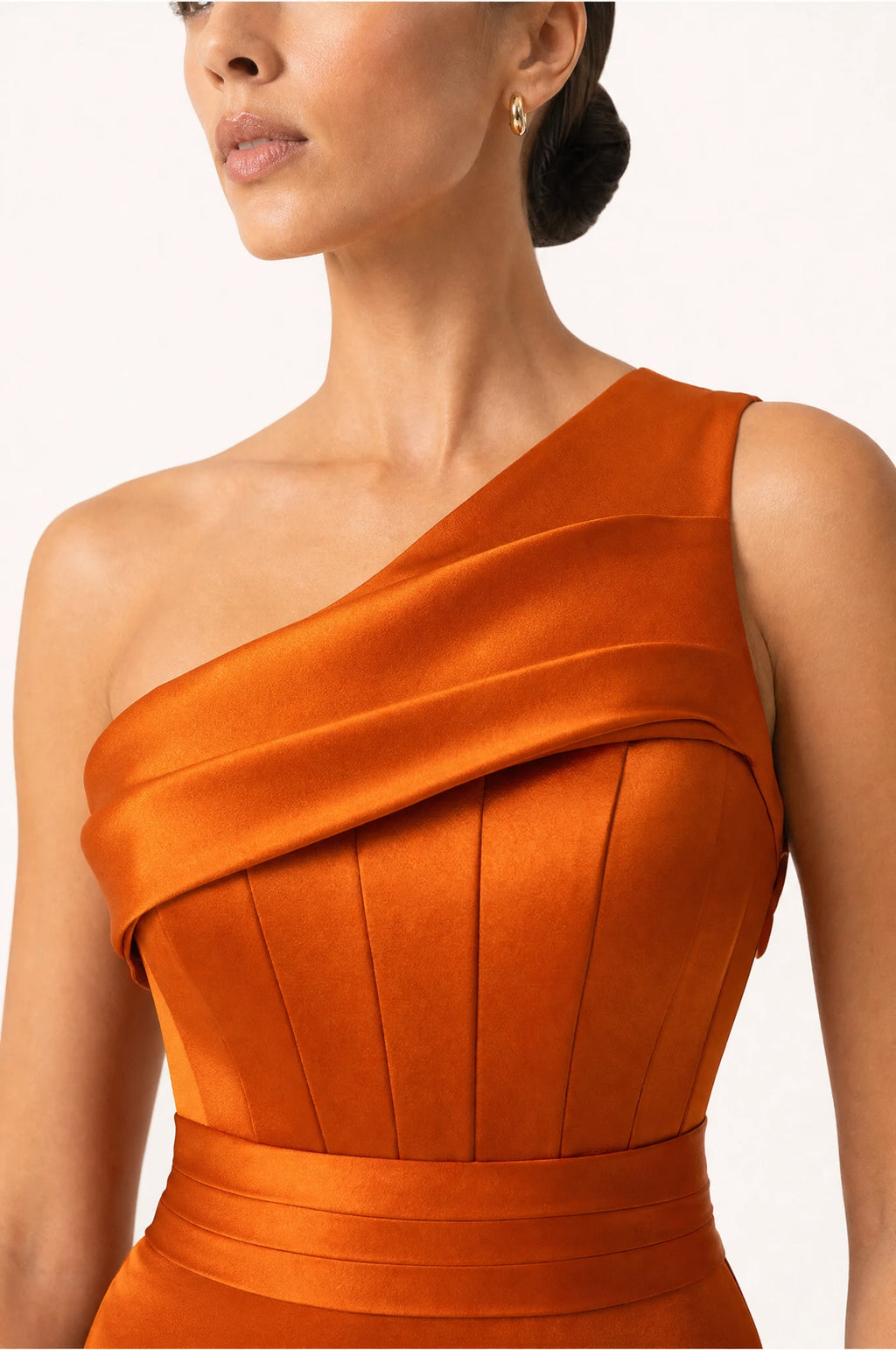 Gros plan sur le bustier structuré à fines nervures et le drapé satin de l'épaule unique de la robe demoiselle d'honneur orange Pénélope, détail du tissu satiné
